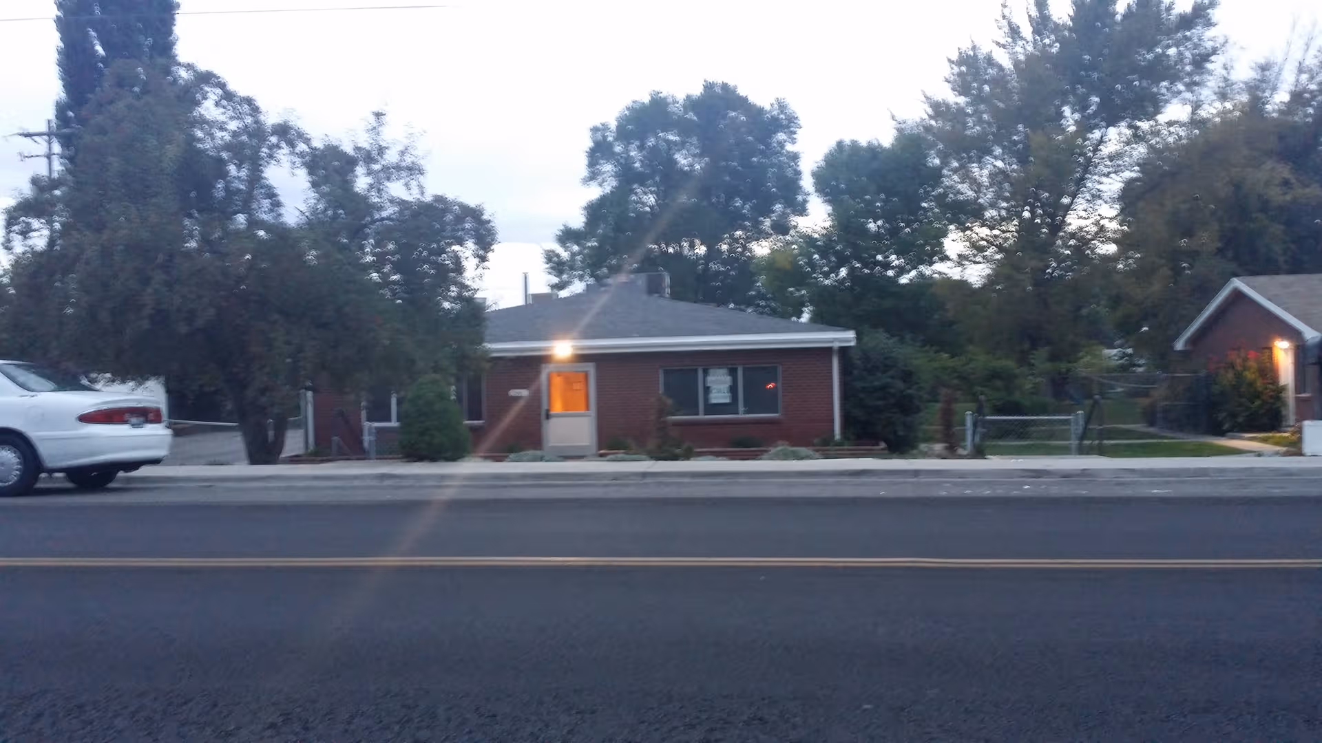 Brick care center along a street with trees and a parked car in front.