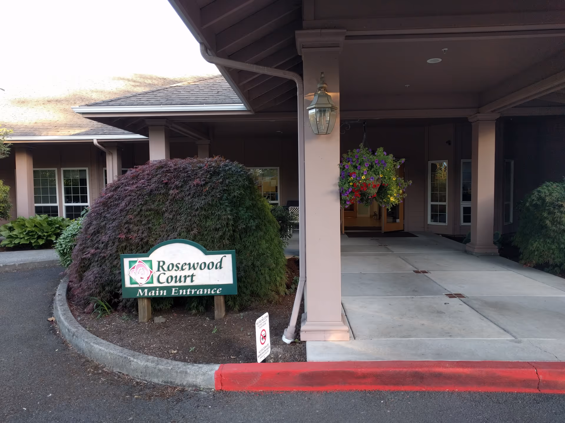 Exterior view of Rosewood Court main entrance with hanging planter, canopy, and sign.