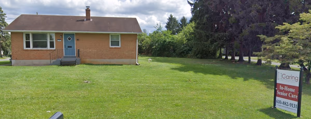 A single-story brick building with a blue front door sits on a green lawn.