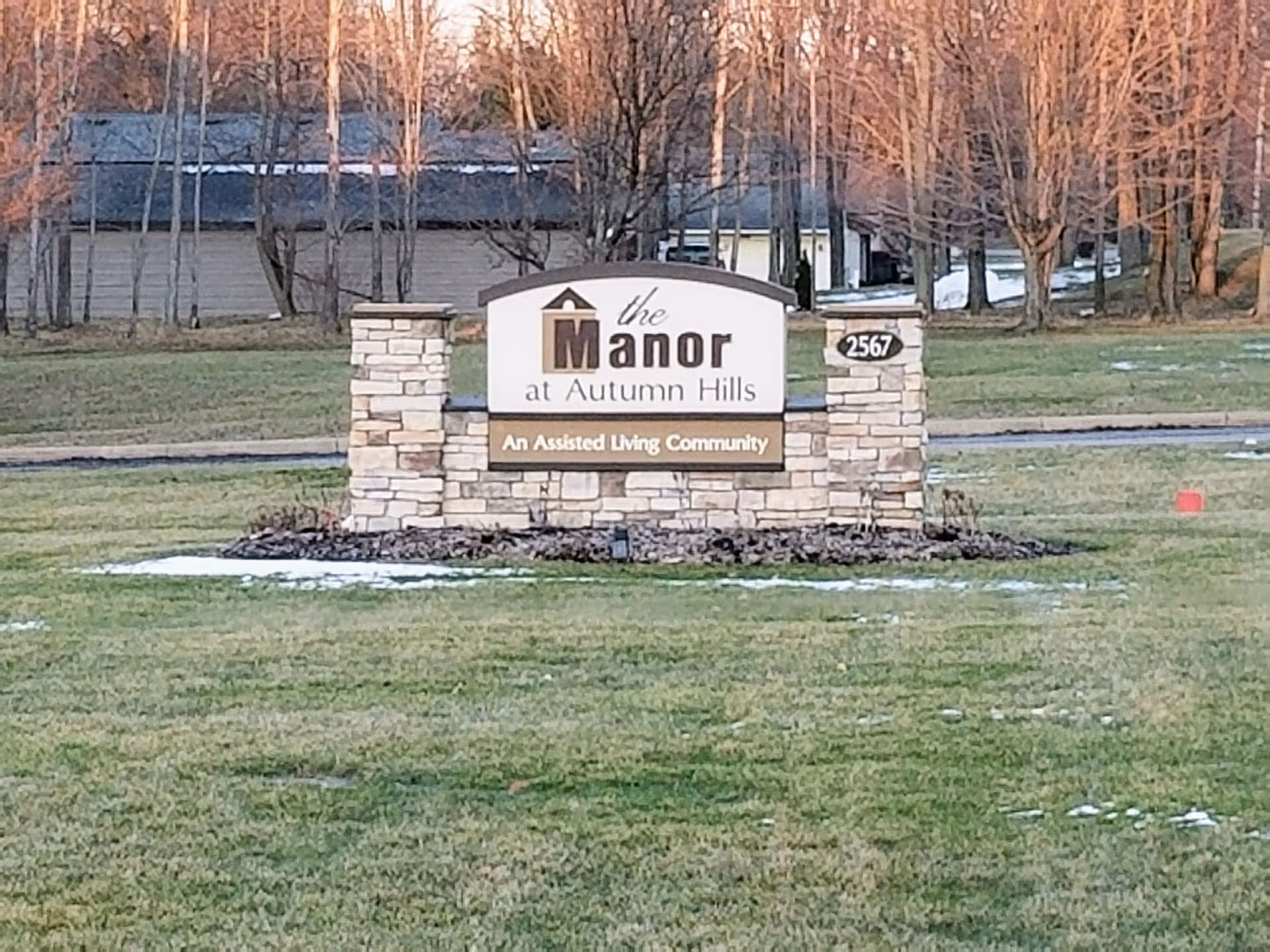 Stone entrance sign reads 'the Manor at Autumn Hills' with 'An Assisted Living Community'.