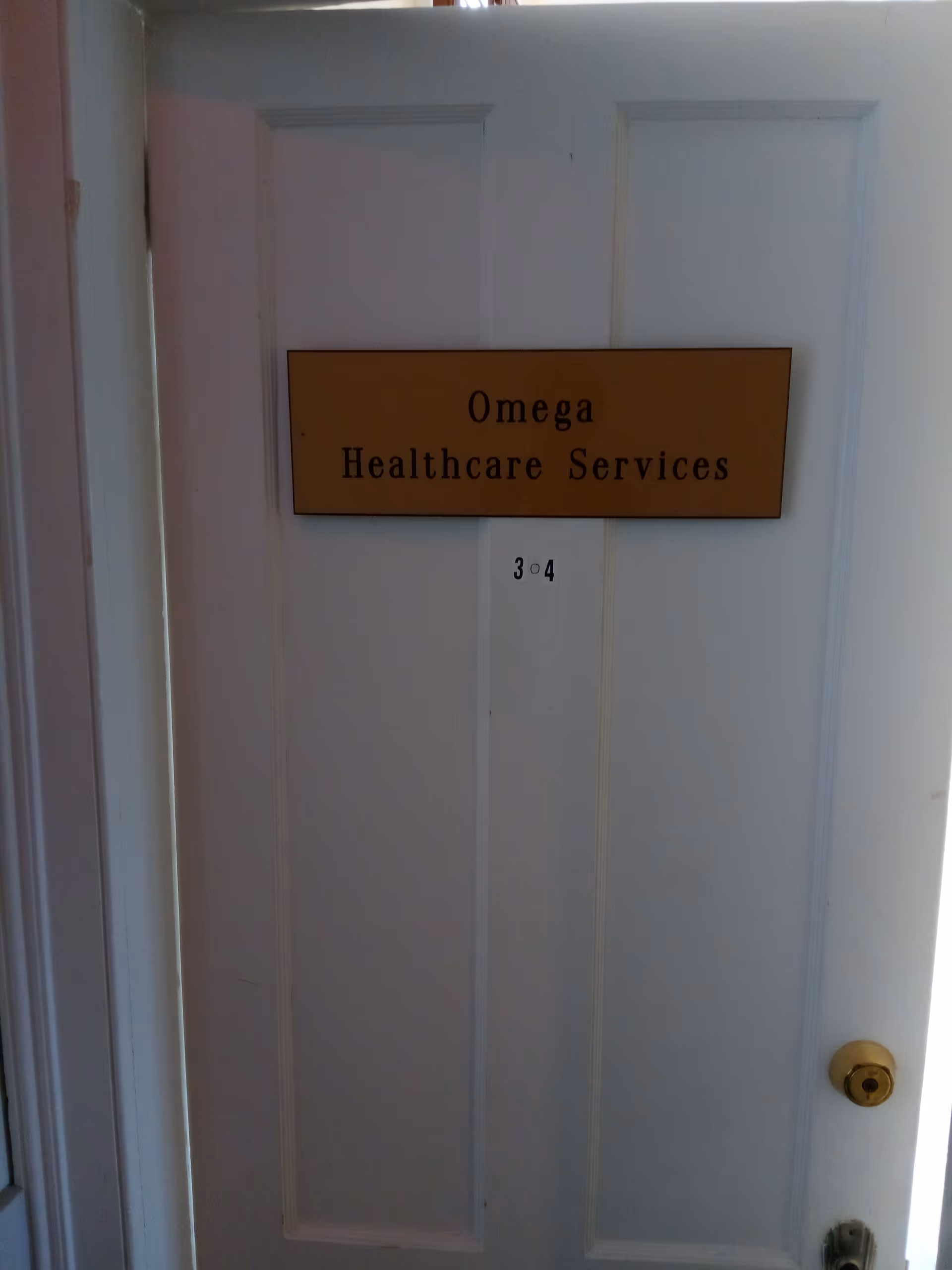 White interior door with Omega Healthcare Services plaque and room number 304