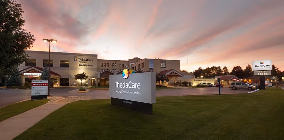 Exterior view of ThedaCare Medical Center-New London at sunset with sign and parking lot.