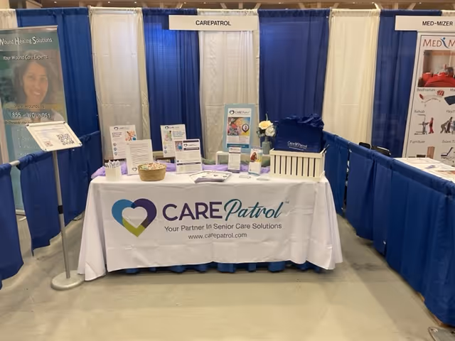 Indoor CarePatrol of Rochester expo booth with table, banners, and literature.