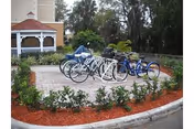 Bicycles parked on a circular outdoor courtyard with landscaped beds near a building.