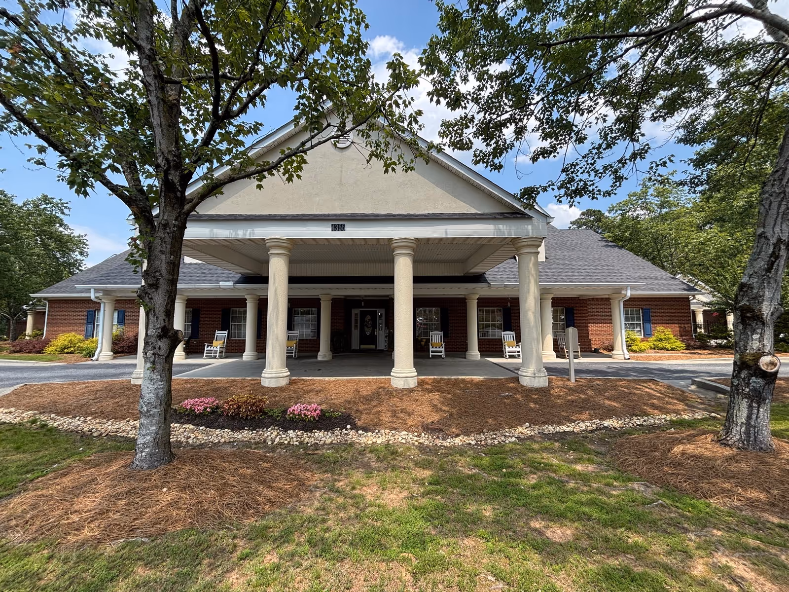 Front entrance of a brick senior living facility with a covered portico and tall columns.