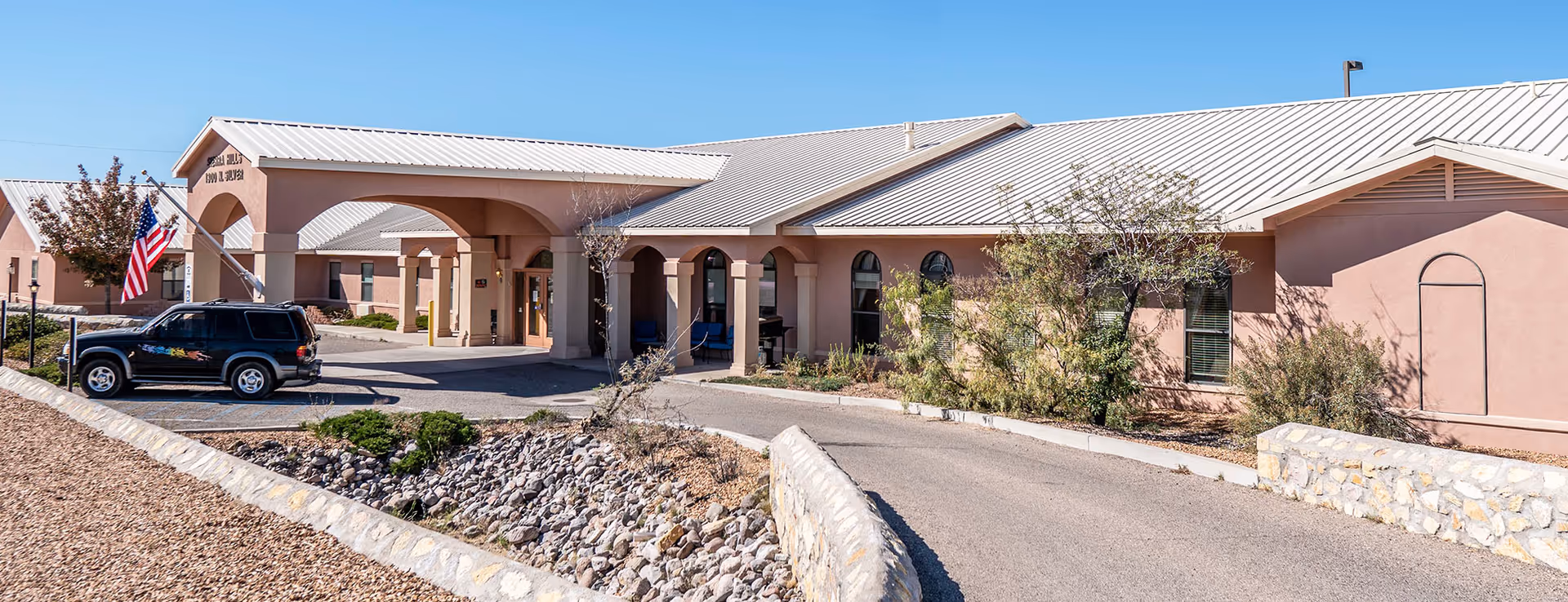 Front exterior of Sierra Hill Assisted Living showing entrance, arches, and a parked SUV.
