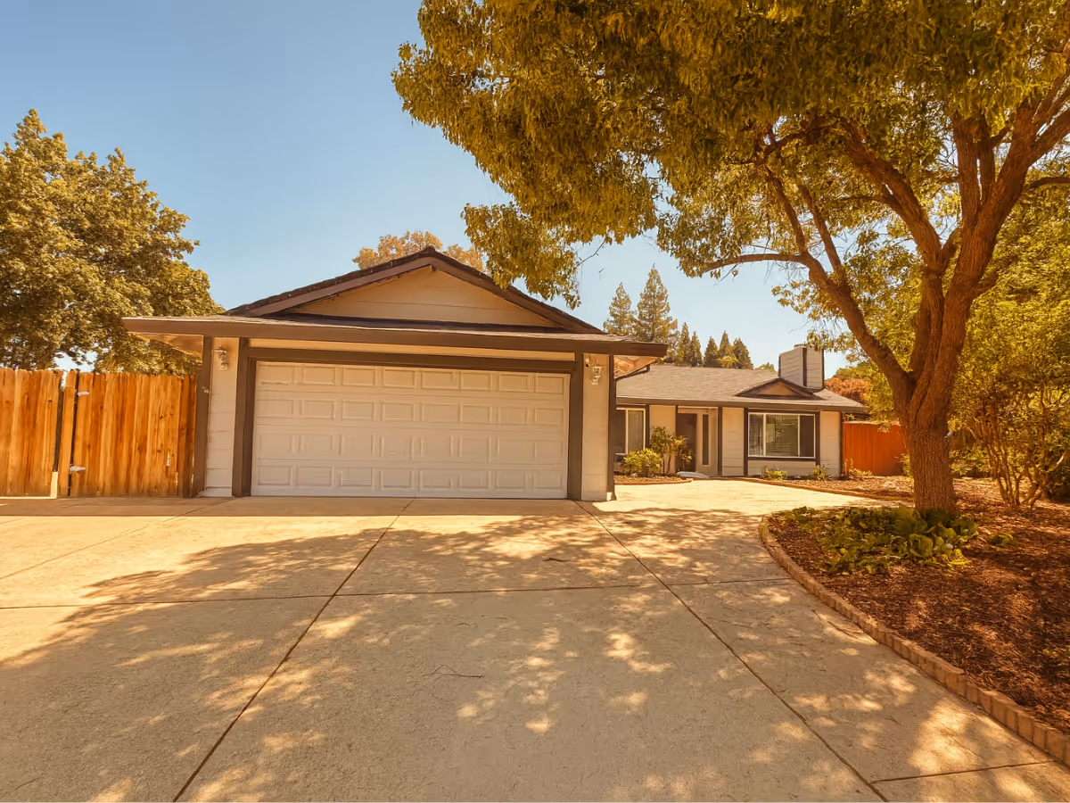 Front exterior of a single-story facility with a garage, driveway, and large tree.