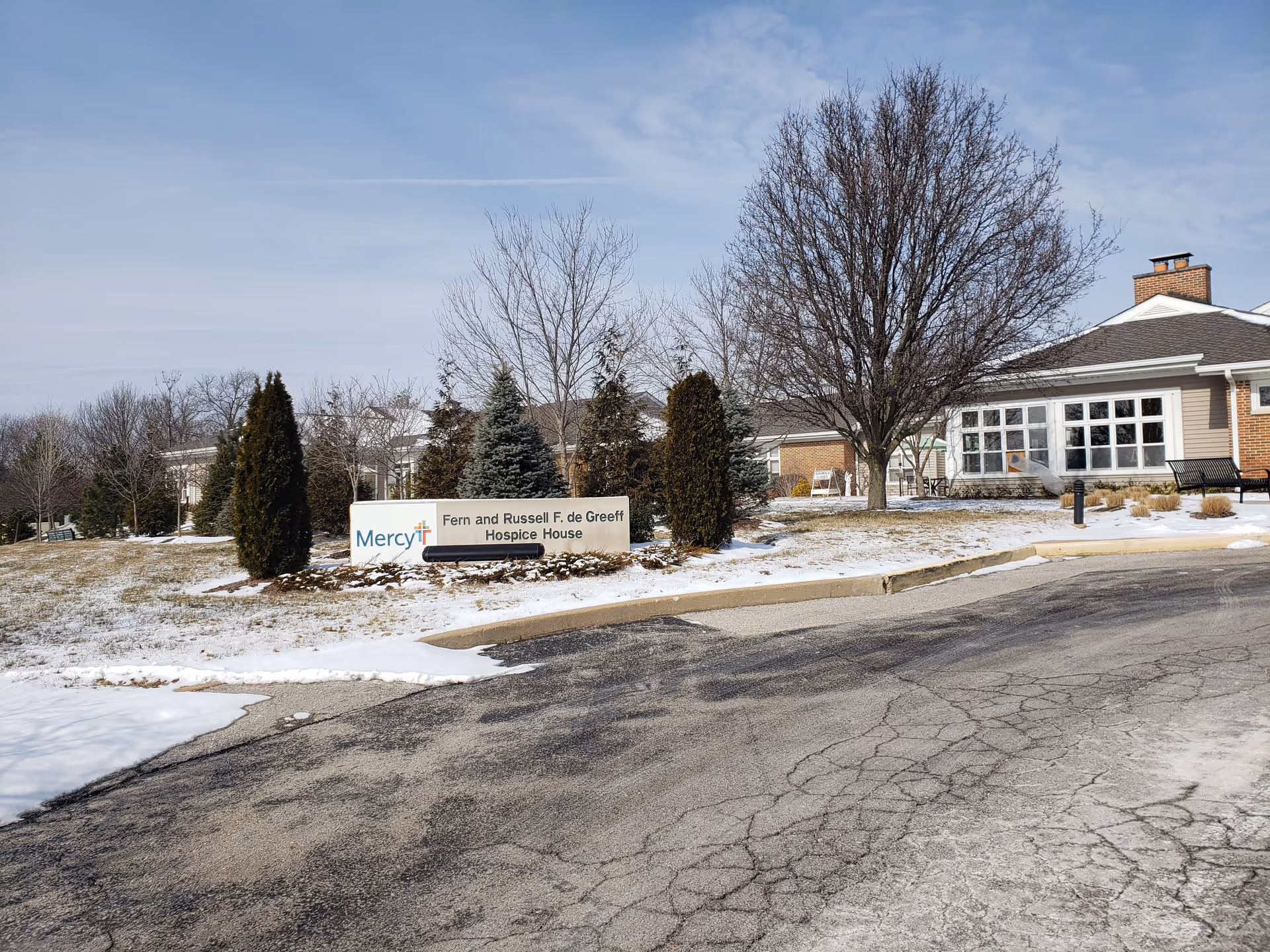 Exterior view of Mercy Hospice building with sign and snow-covered landscape