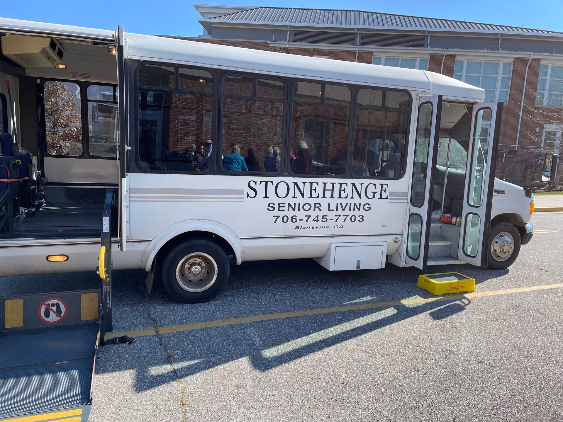 Stonehenge Senior Living bus with passengers visible inside, doors open.