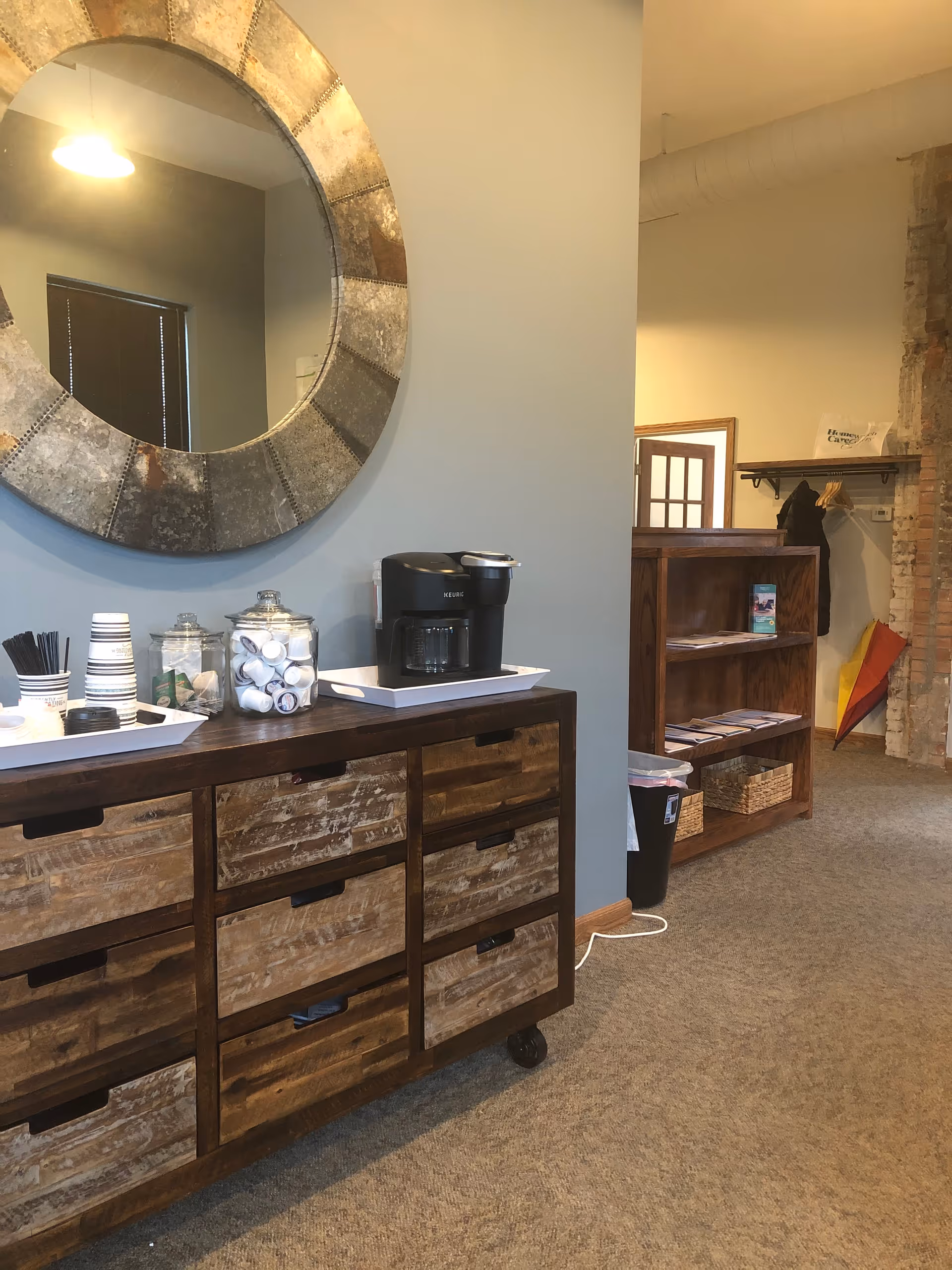 Common area coffee station with jars, cups, and a large circular mirror.