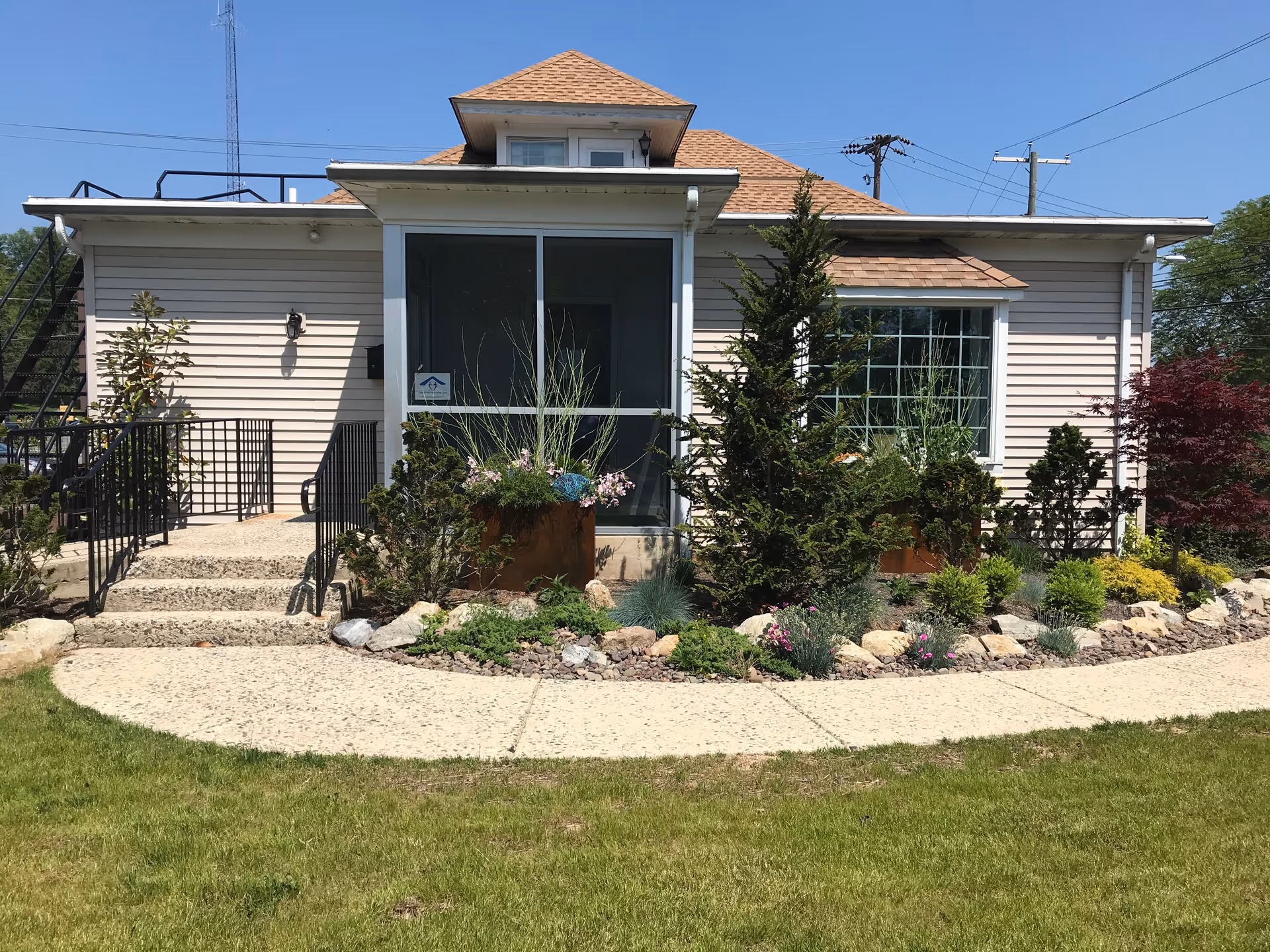 Front view of a small beige building with a landscaped entry and walkway