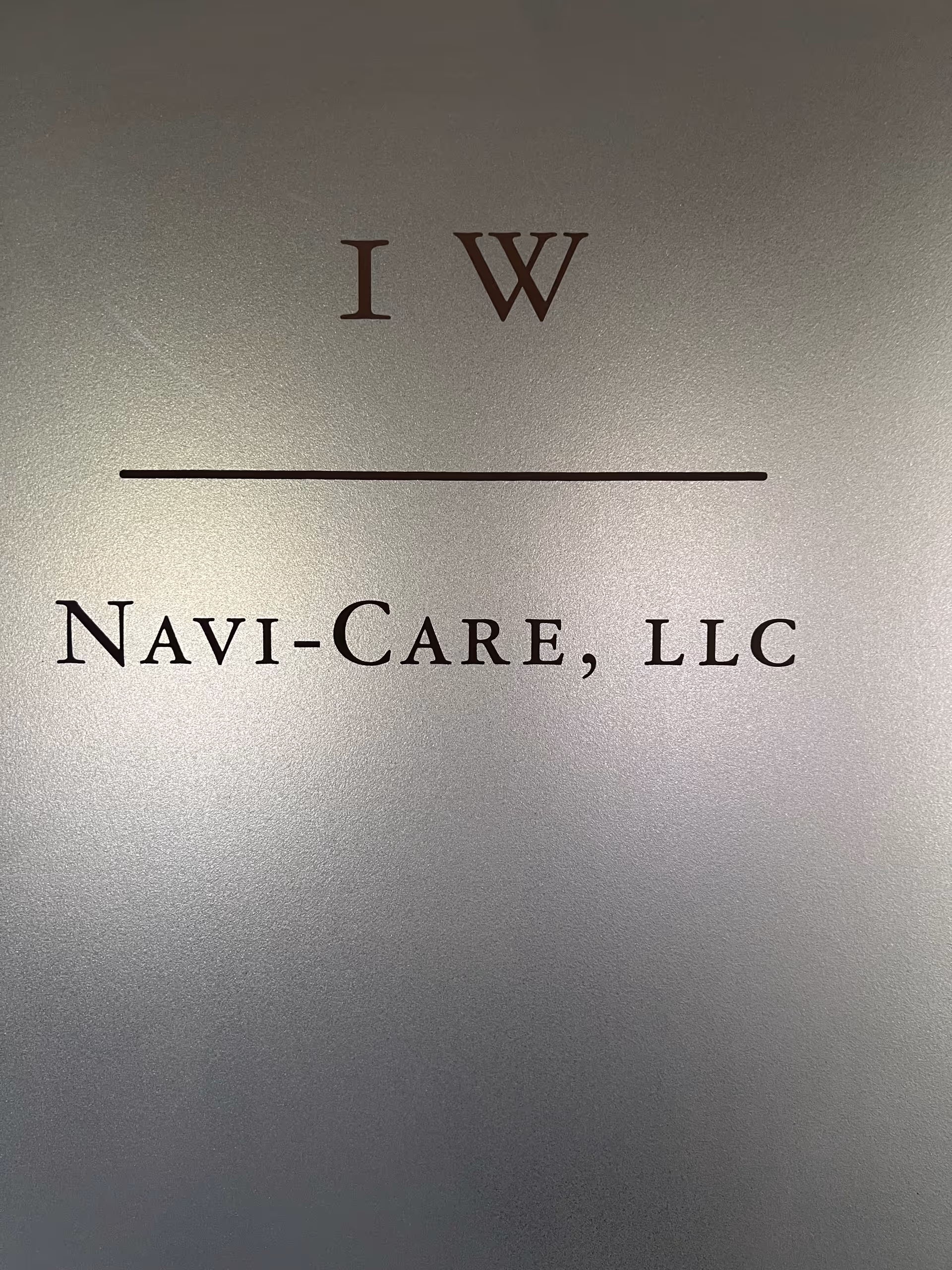 Metal sign plaque displays Navi-Care, LLC with IW letters above a line.