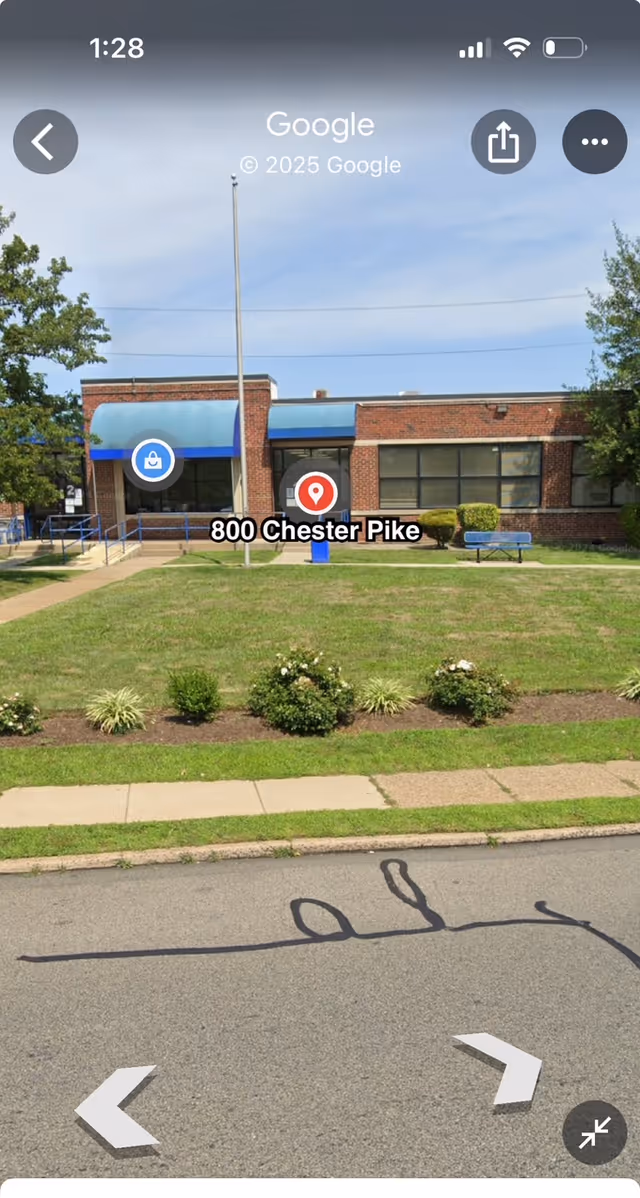 Exterior view of a brick senior living facility with blue awnings and address 800 Chester Pike.