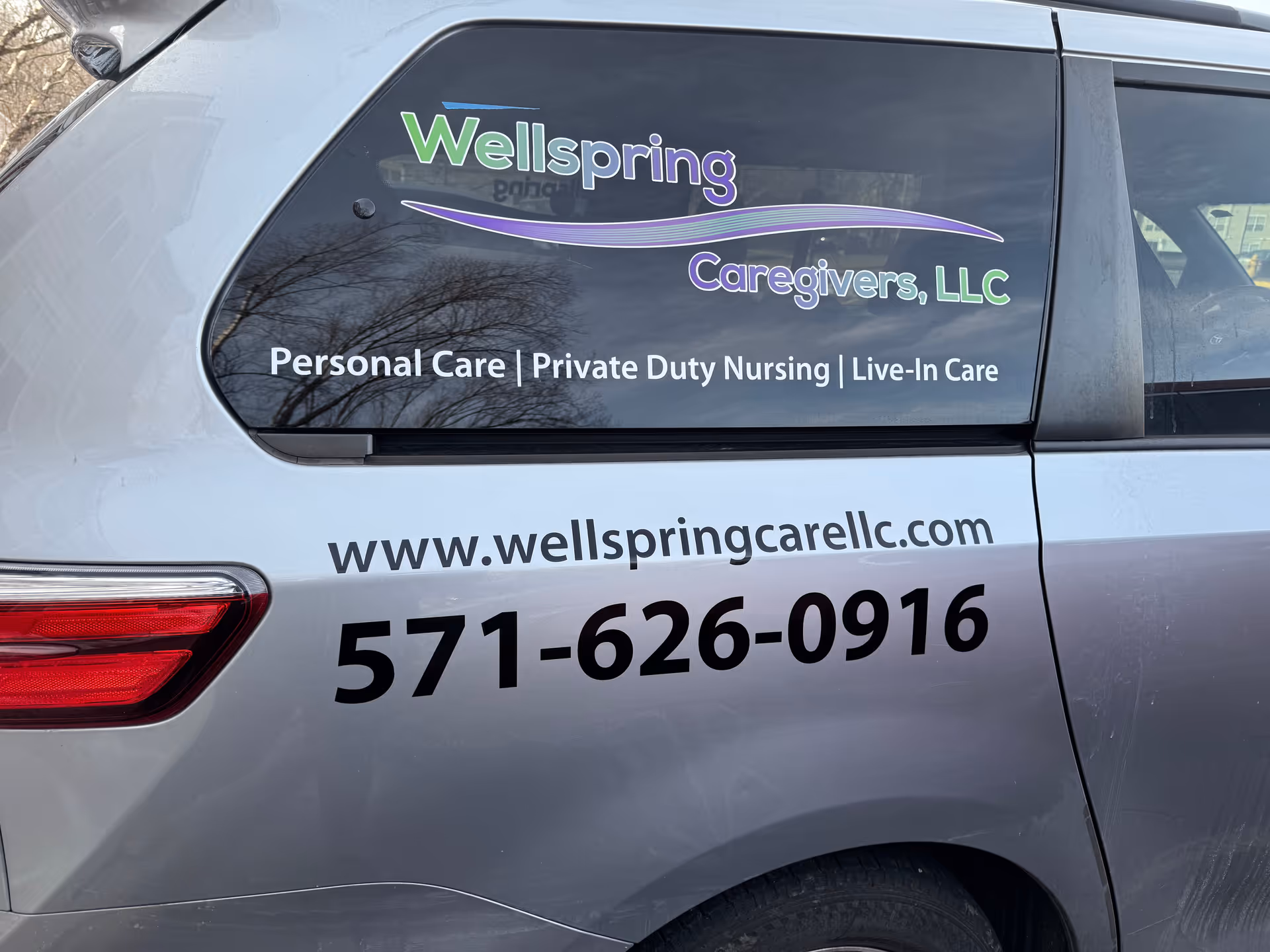 Side of a Wellspring Caregivers LLC van displaying logo and contact information.