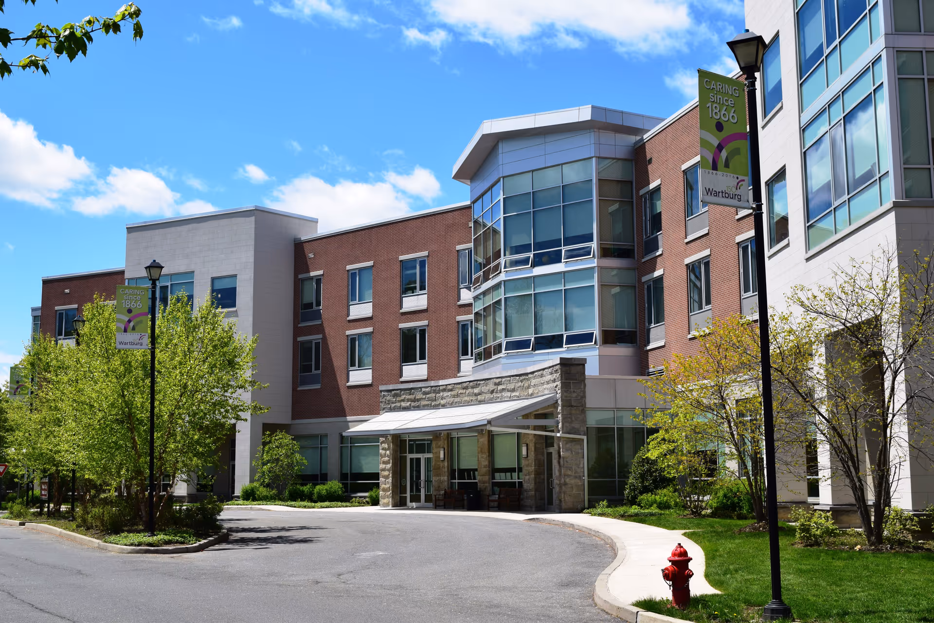 Exterior view of The Wartburg Home senior living facility with entrance and banners.
