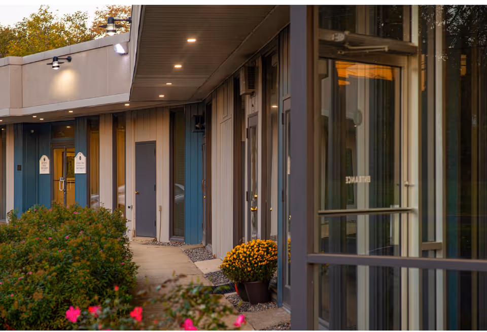 Exterior walkway along a senior living facility with doors and plants.