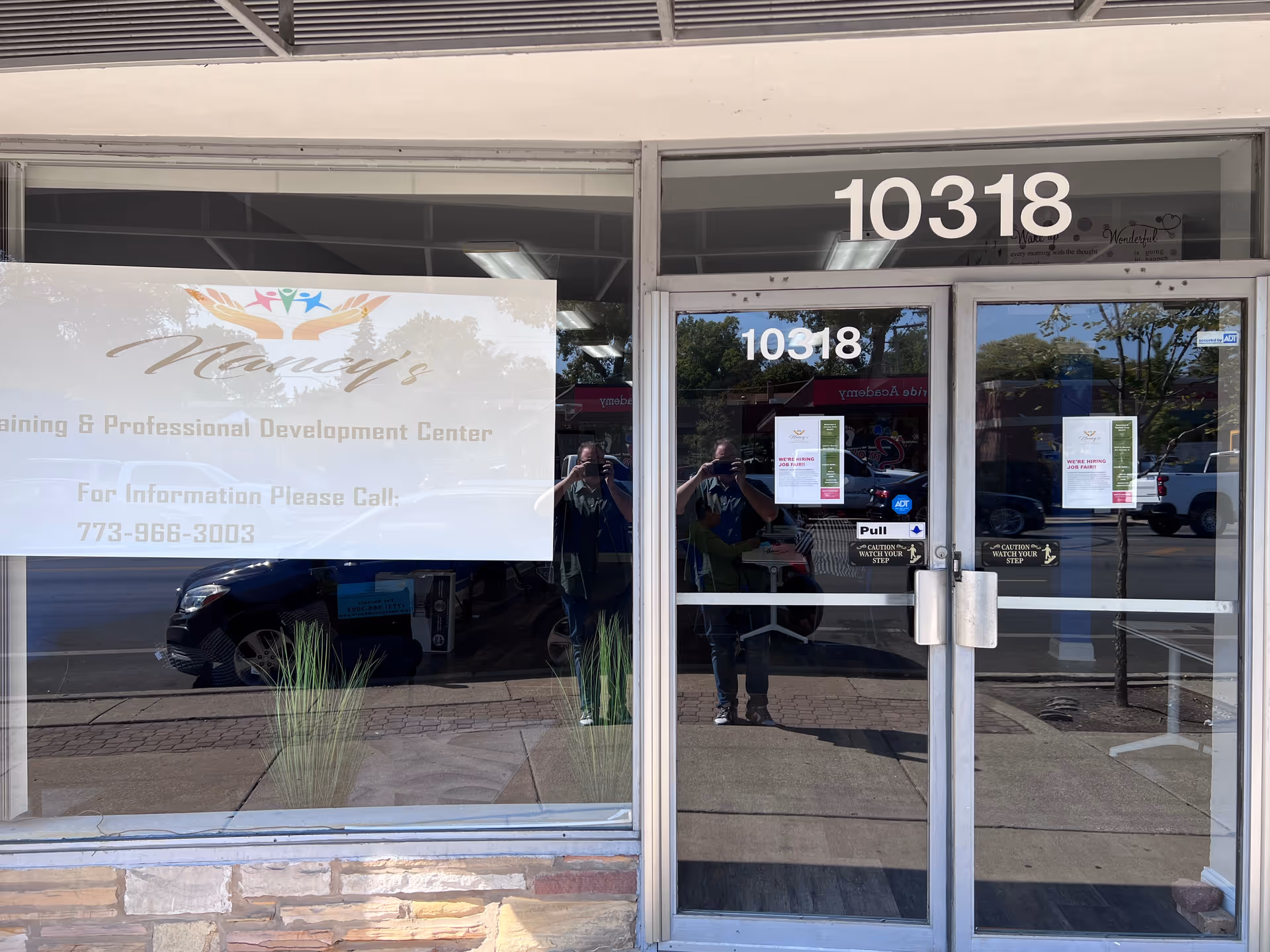 Storefront entrance for Nancy's Home Care Training Center with a large banner and glass doors.