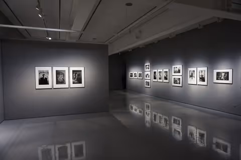 A spacious interior gallery with framed black-and-white photographs on gray walls.