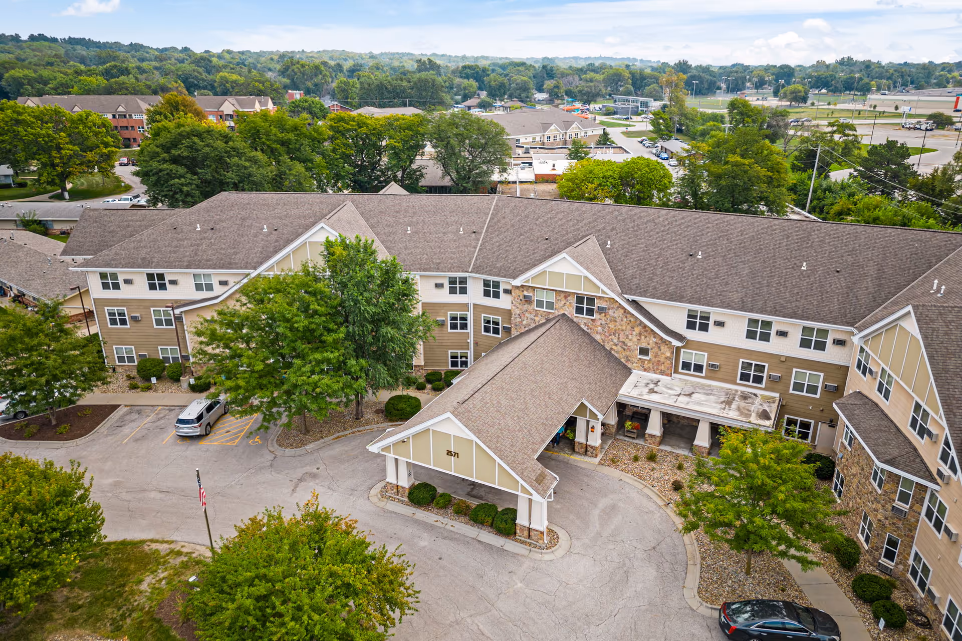Aerial view of a multi-wing senior living center with parking and surrounding trees.