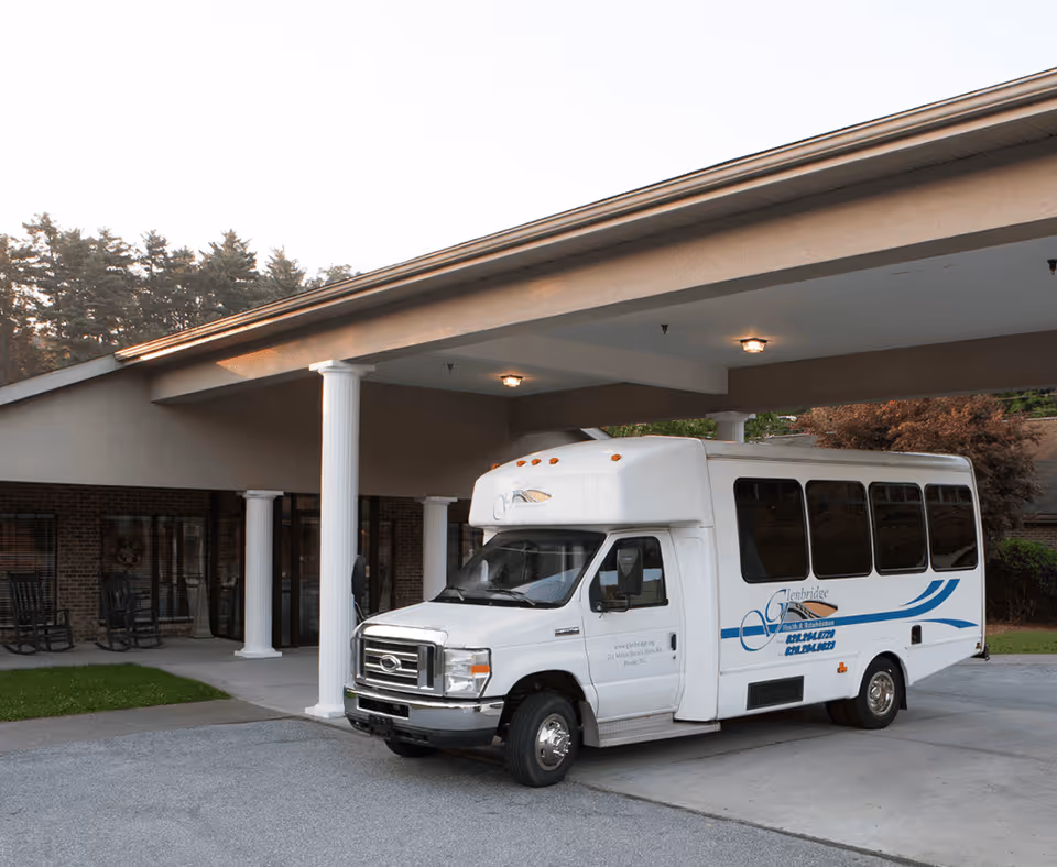 White shuttle bus parked at the entrance of Glenbridge Health and Rehabilitation Center.