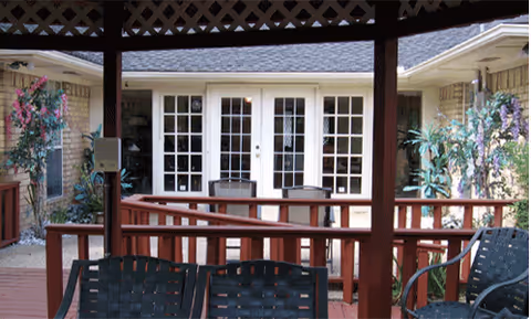 Covered outdoor patio with wicker chairs and French doors.