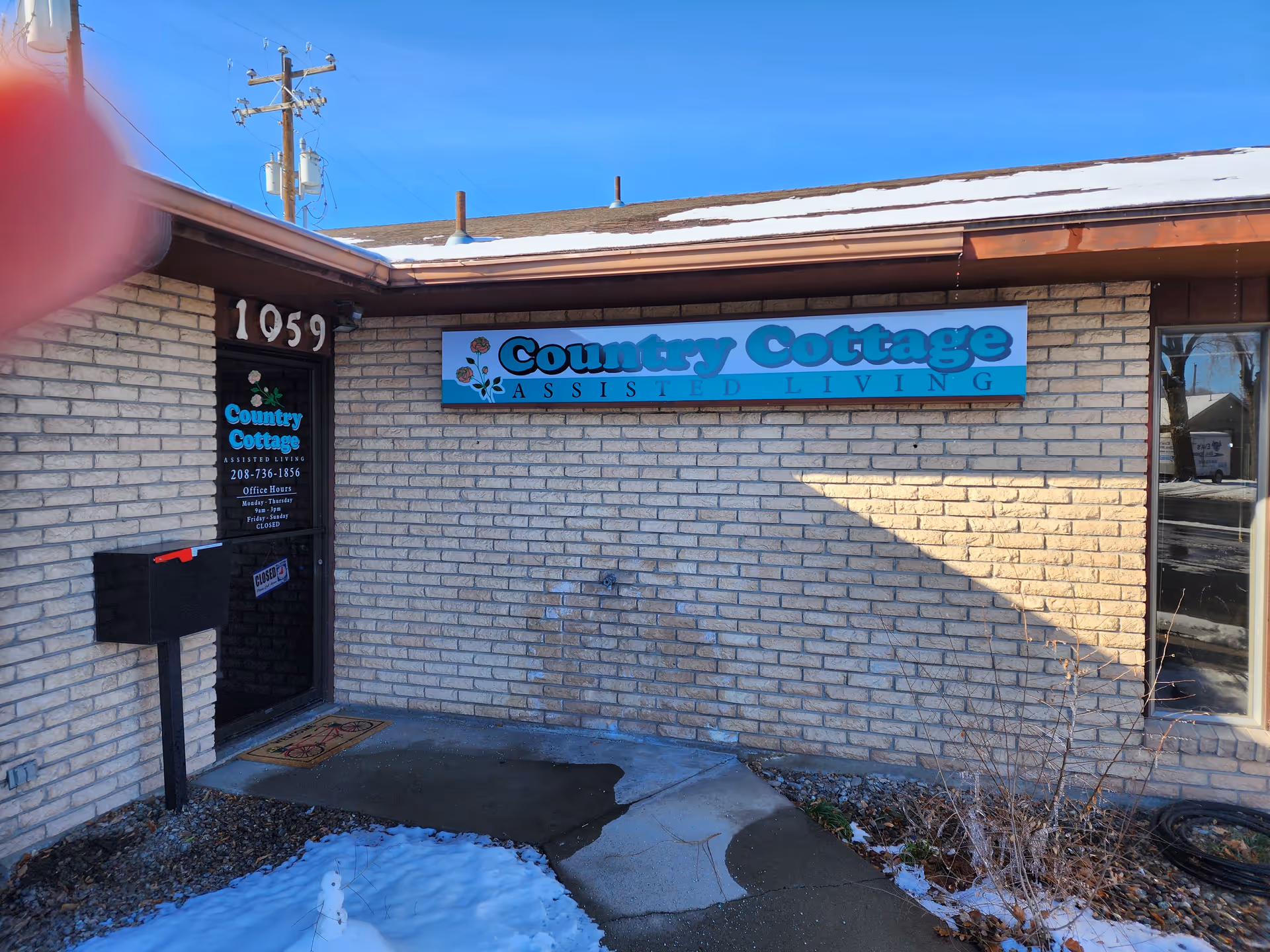 Brick exterior of Country Cottage Assisted Living with a blue sign above the entrance.