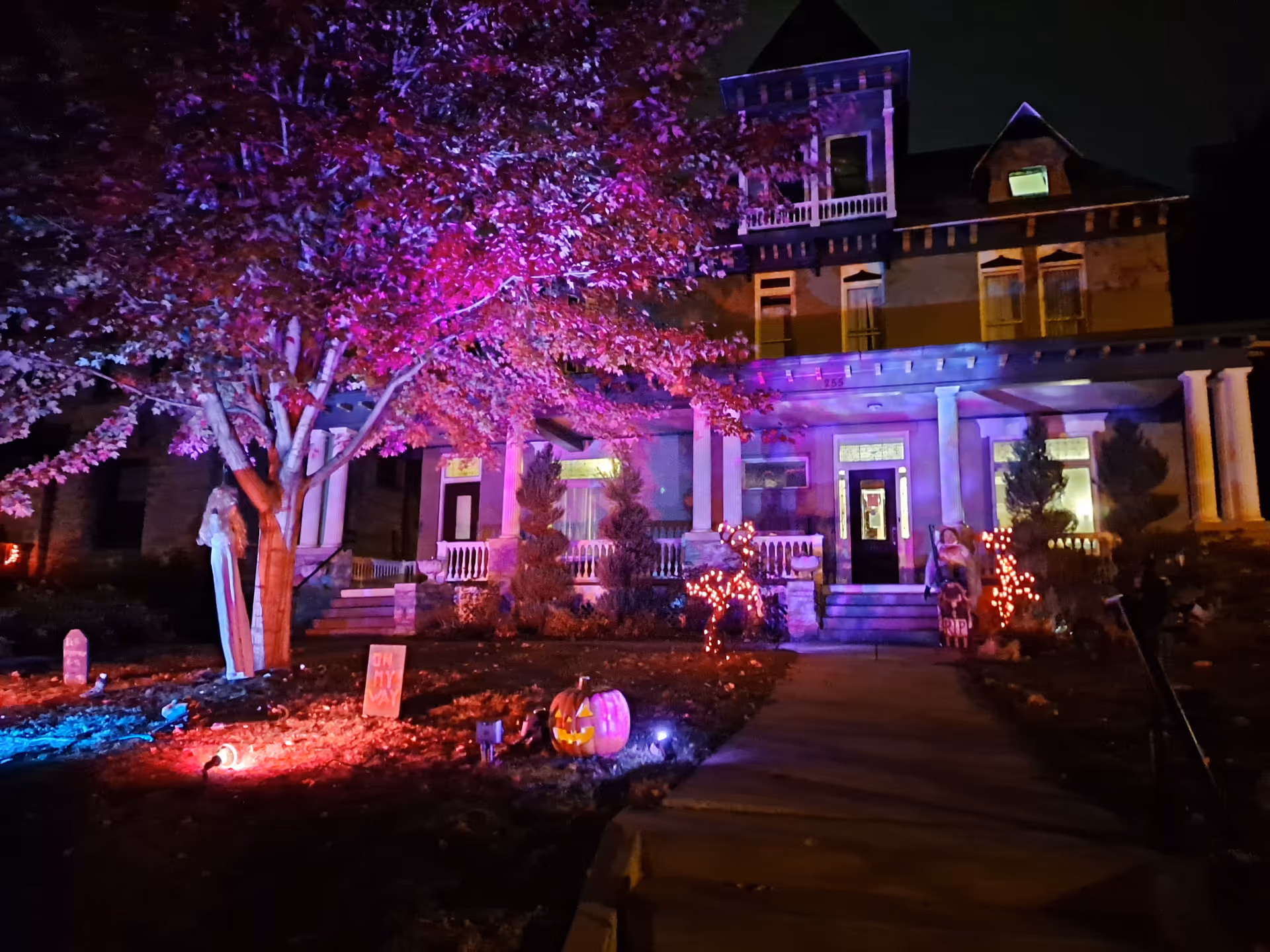 A large front of a building lit with colorful Halloween decorations at night.