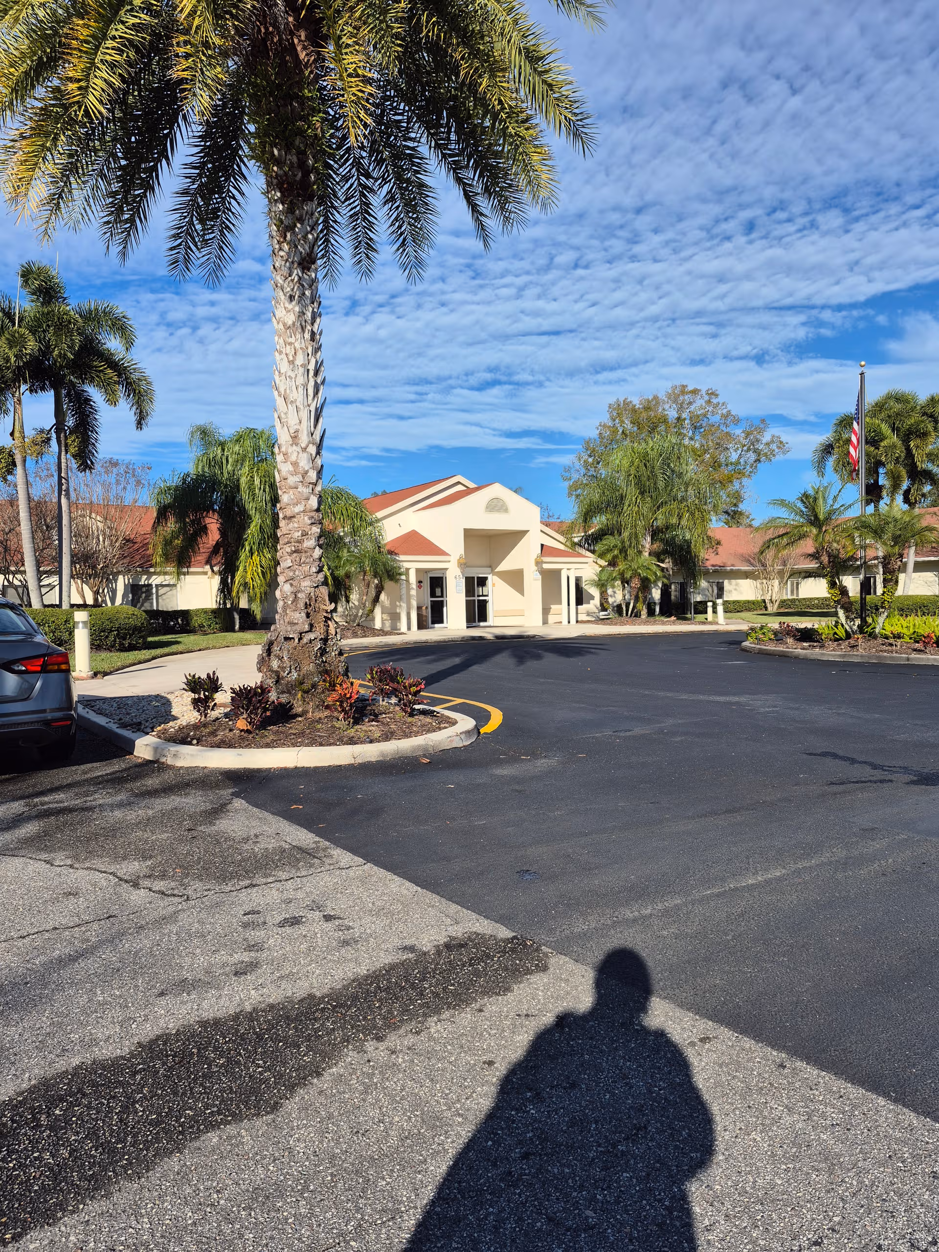 Front entrance with palm trees and a parking lot at Palm Garden of Orlando.