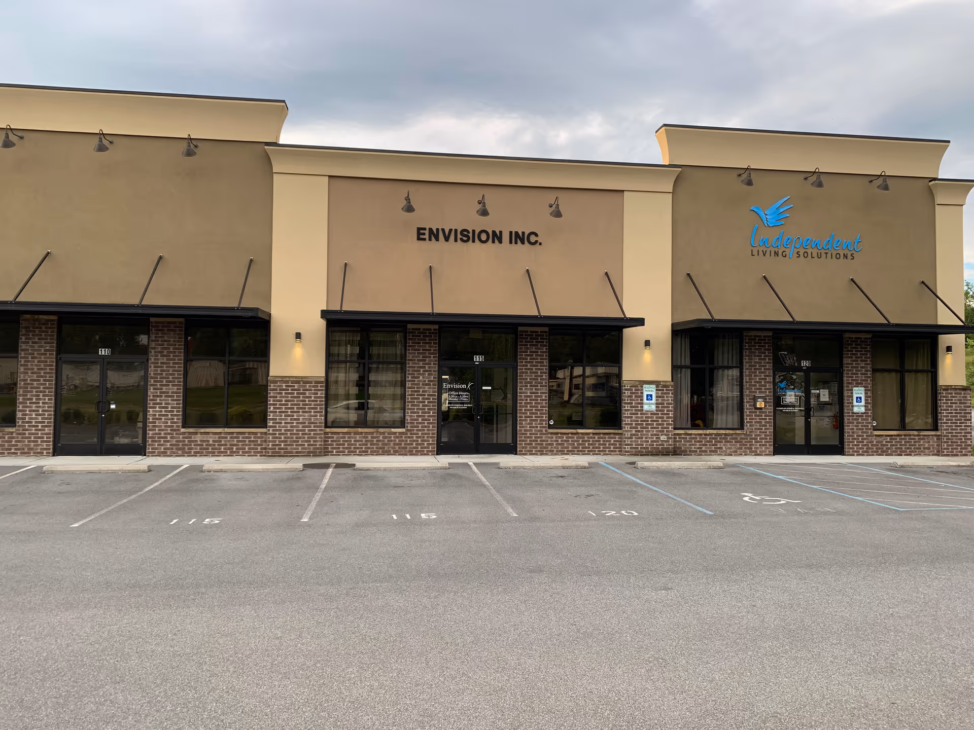 Exterior view of Envision Inc. building with storefronts and parking lot in foreground.