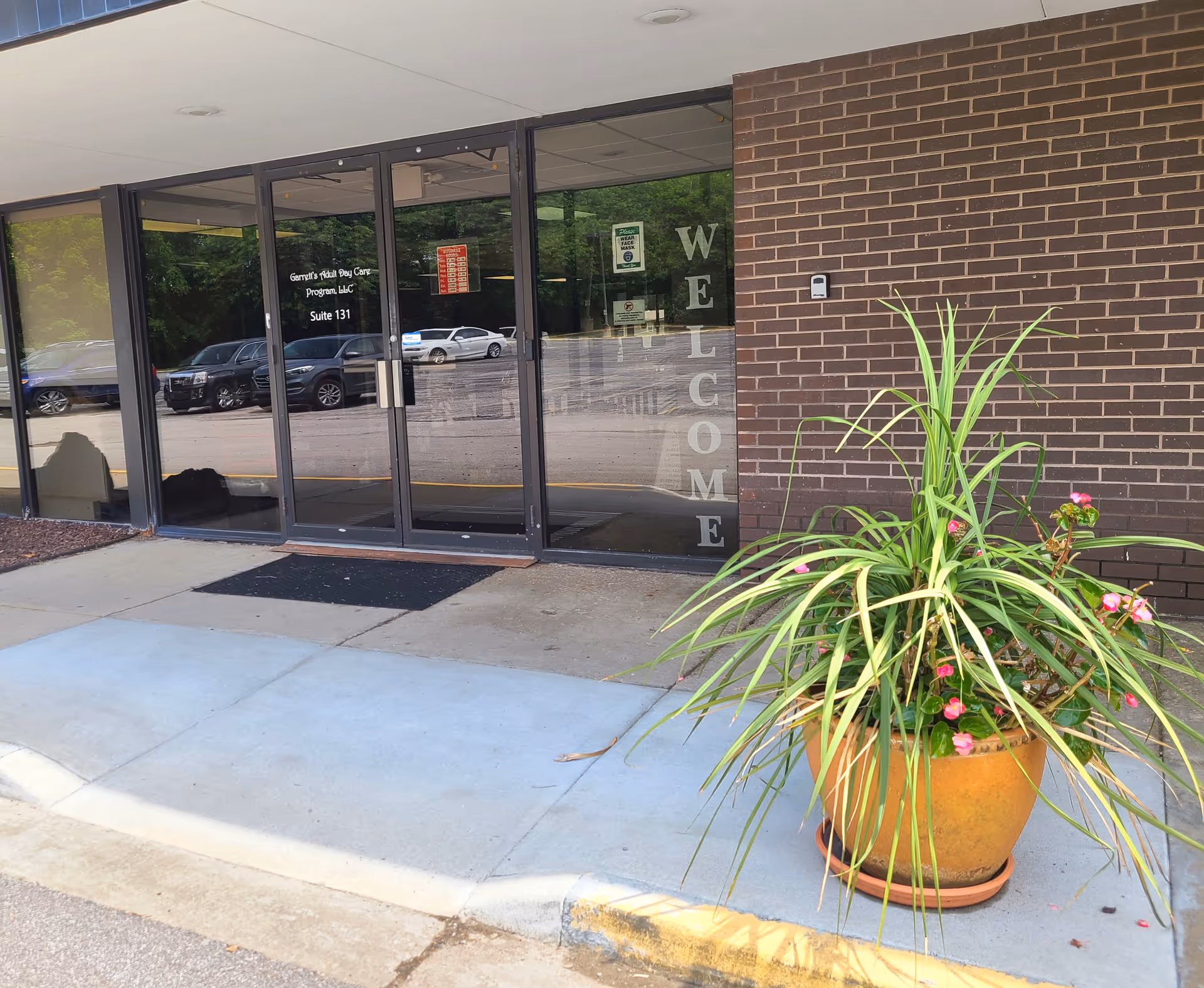 Glass entrance to Garrett's Adult Day Care Program with brick exterior and potted plant.