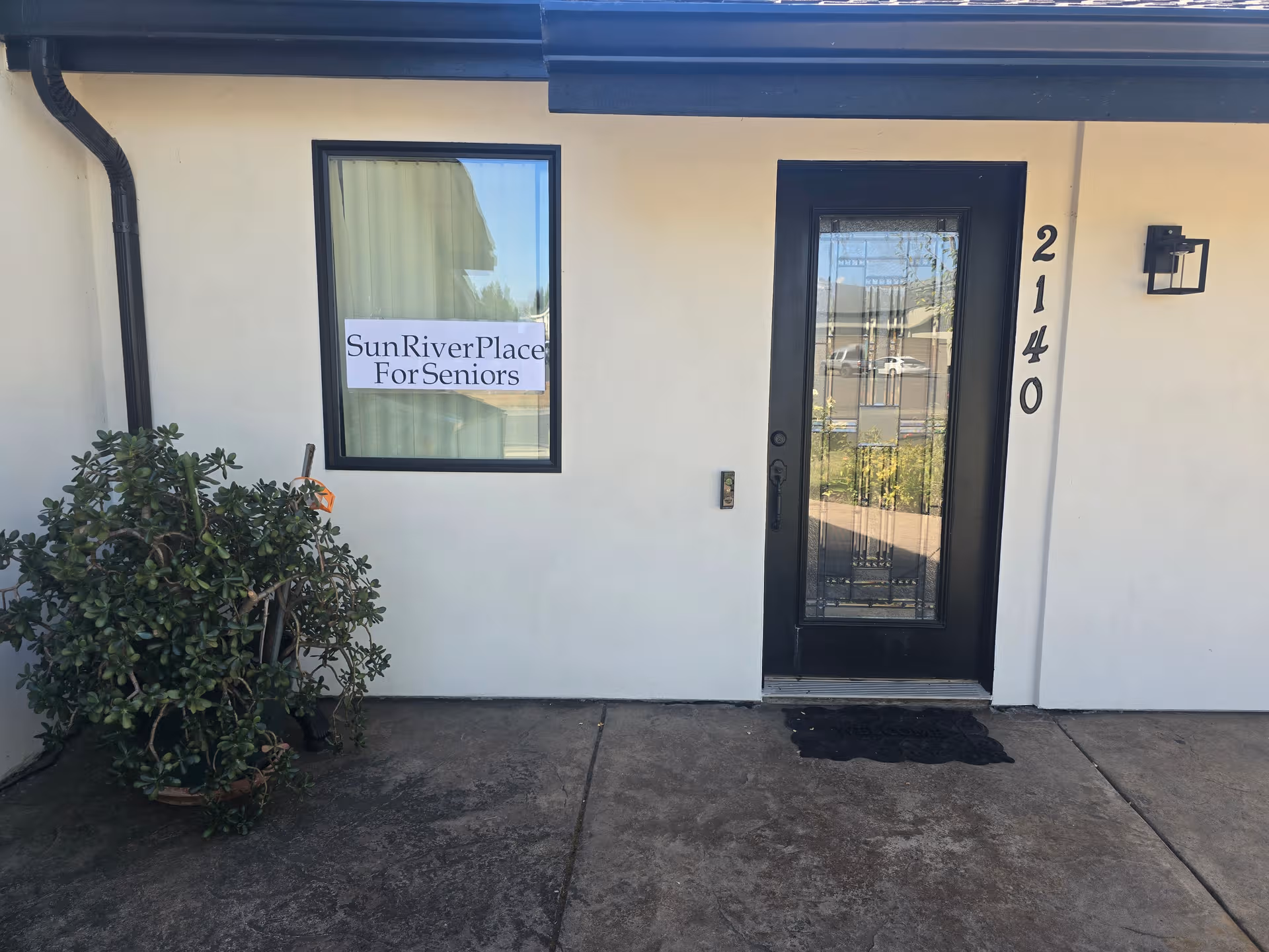 Exterior entrance to Sun River Place for Seniors with glass door and 2140 address