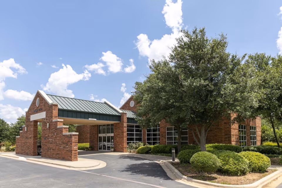 Brick retirement village building with a covered entrance and landscaped surroundings.