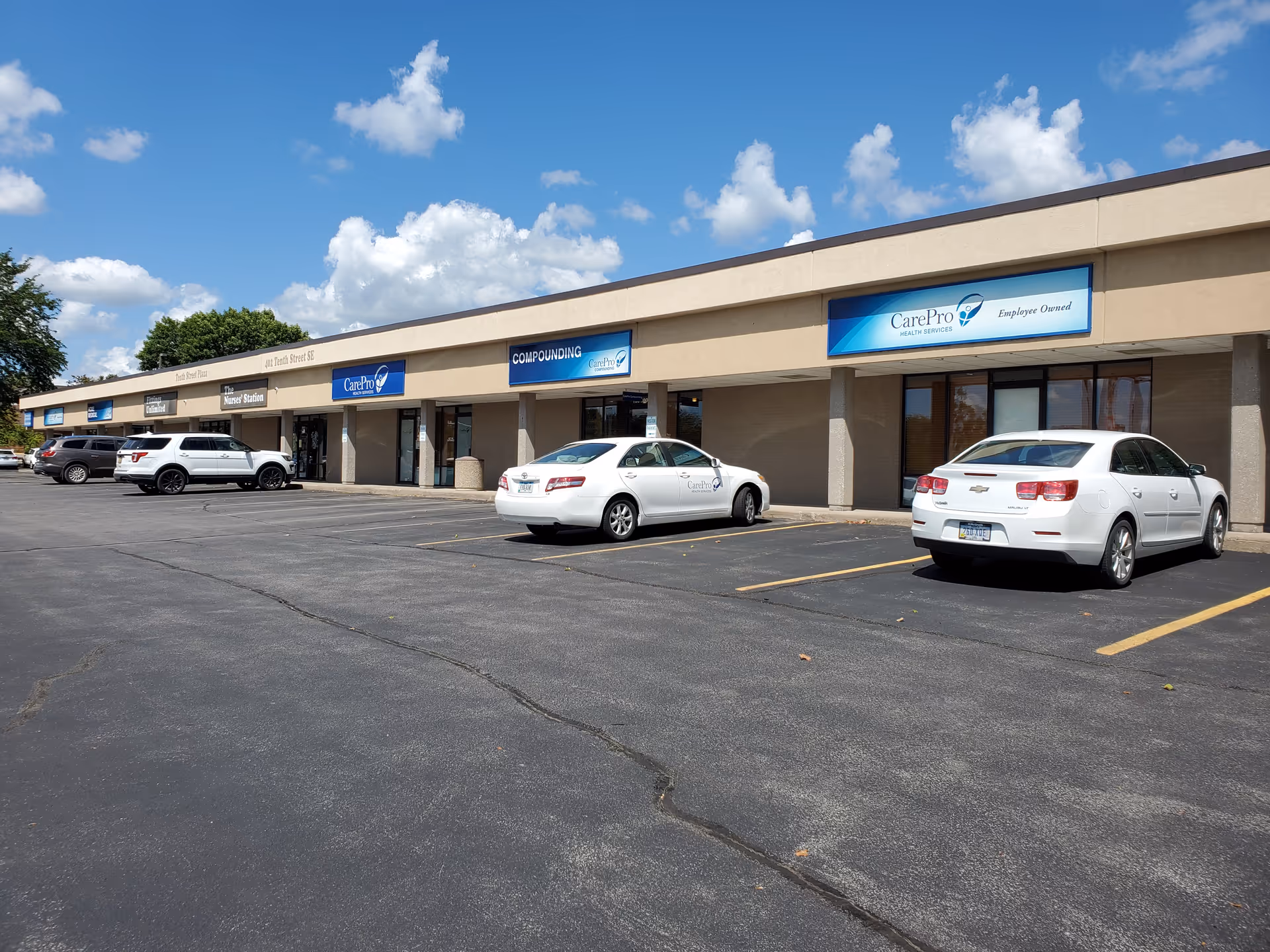 Exterior view of a beige strip mall with CarePro signage and parked cars.