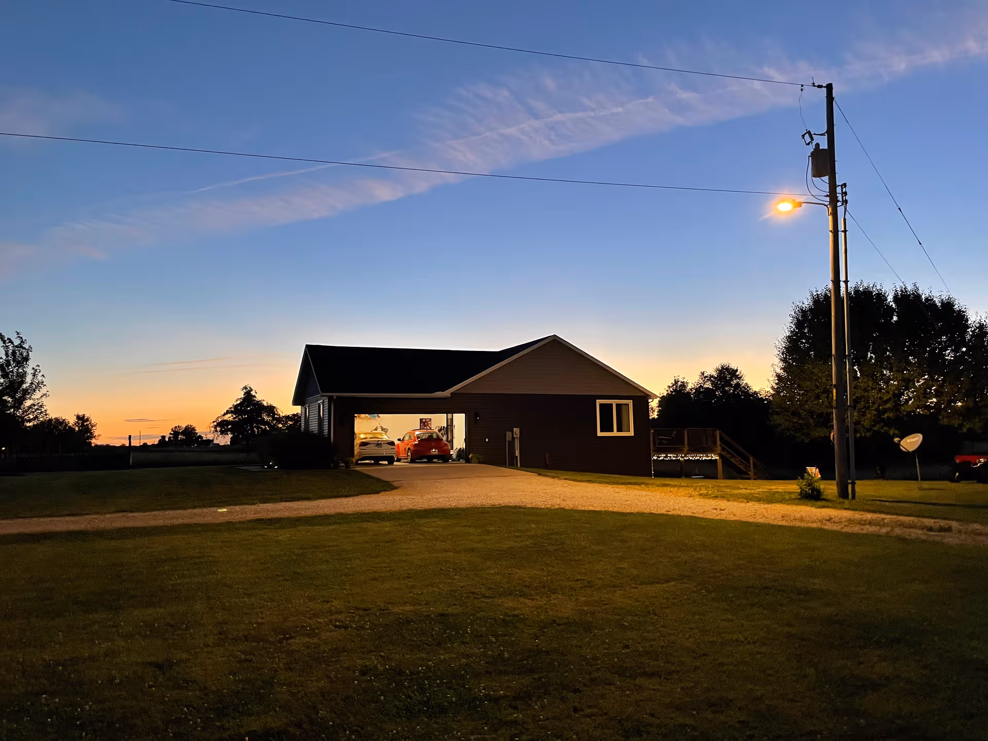 Sunset exterior view of a single-story facility with a driveway and parked cars.