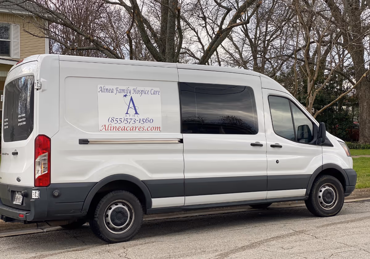 White hospice care van with Alinea Family Hospice Care logo parked on a street.