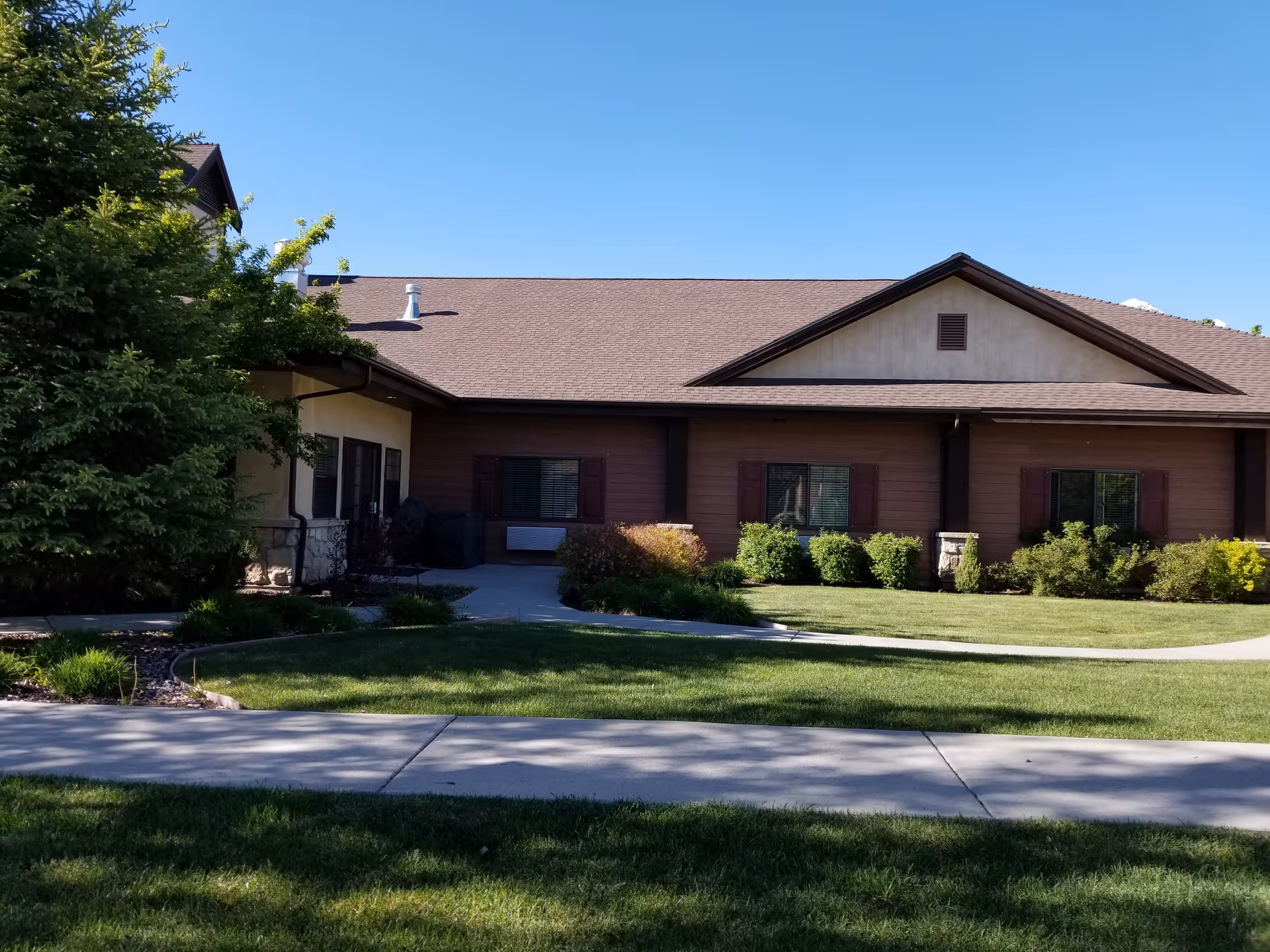 Front view of a single-story River Meadows Senior Living building with lawn and walkway.