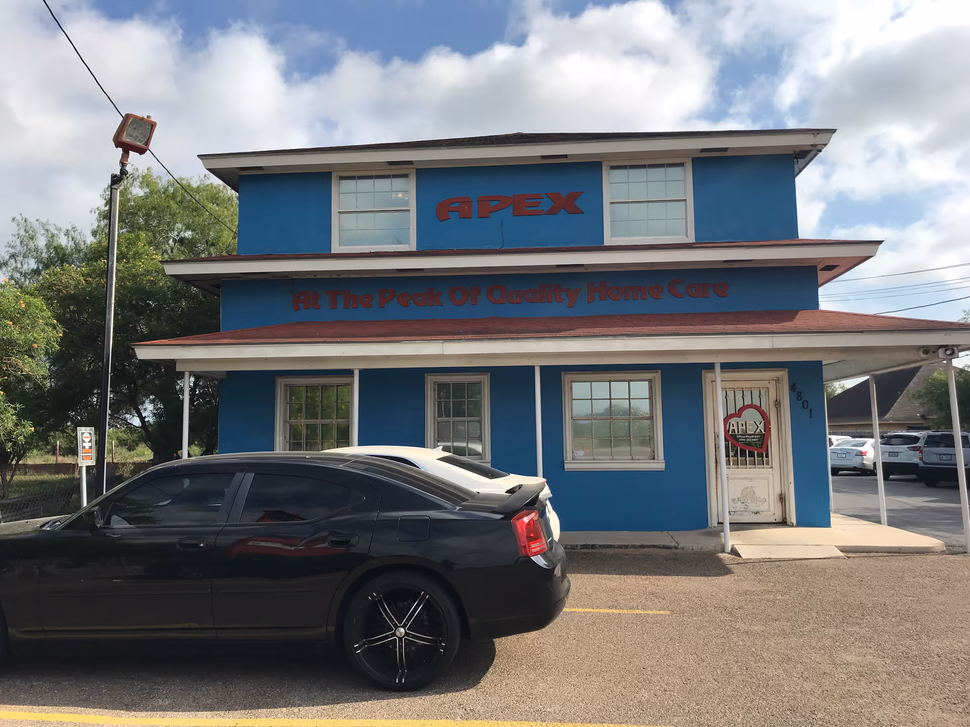 Blue two-story Apex Primary Care building with a black car parked in front.