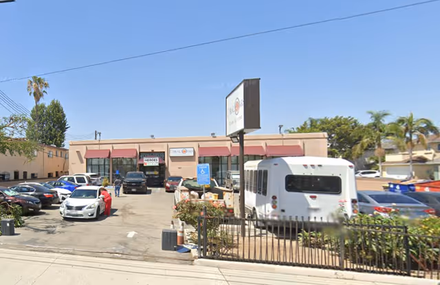 Exterior view of Coral Oaks Care Living building with a parking lot and a white bus.