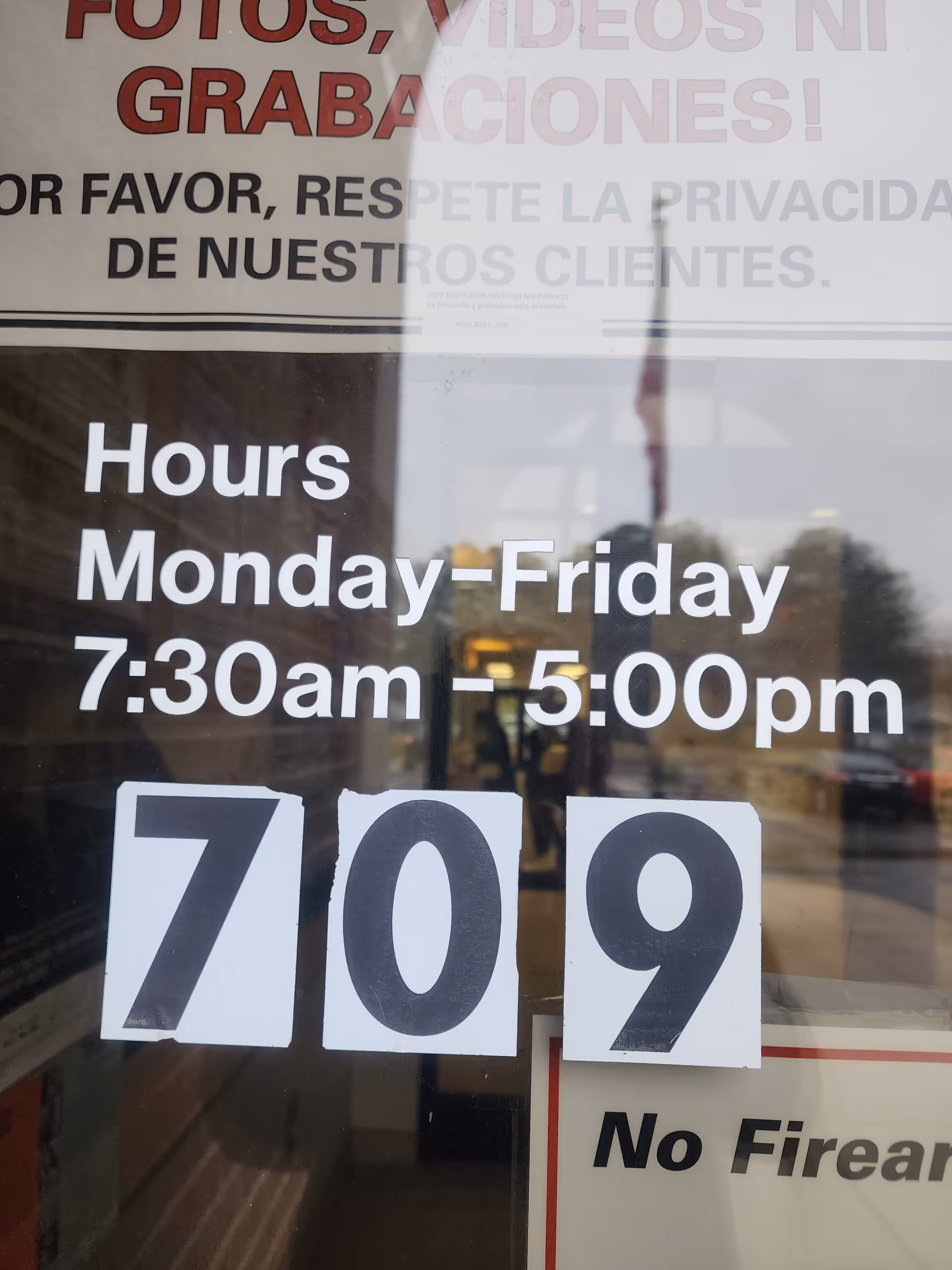 Glass entrance door displays hours and large address numbers for a health department.