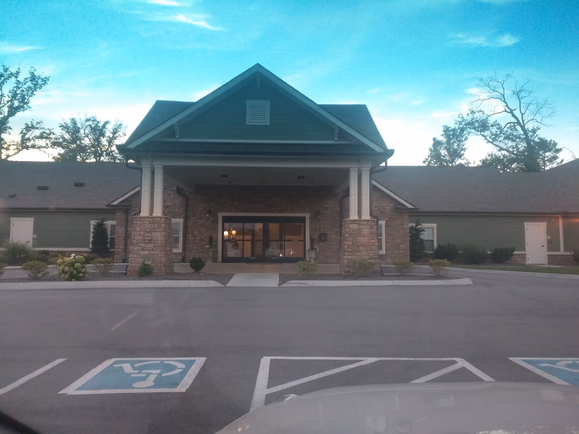 Front view of Clover Hill Senior Living entrance with stone columns and parking.