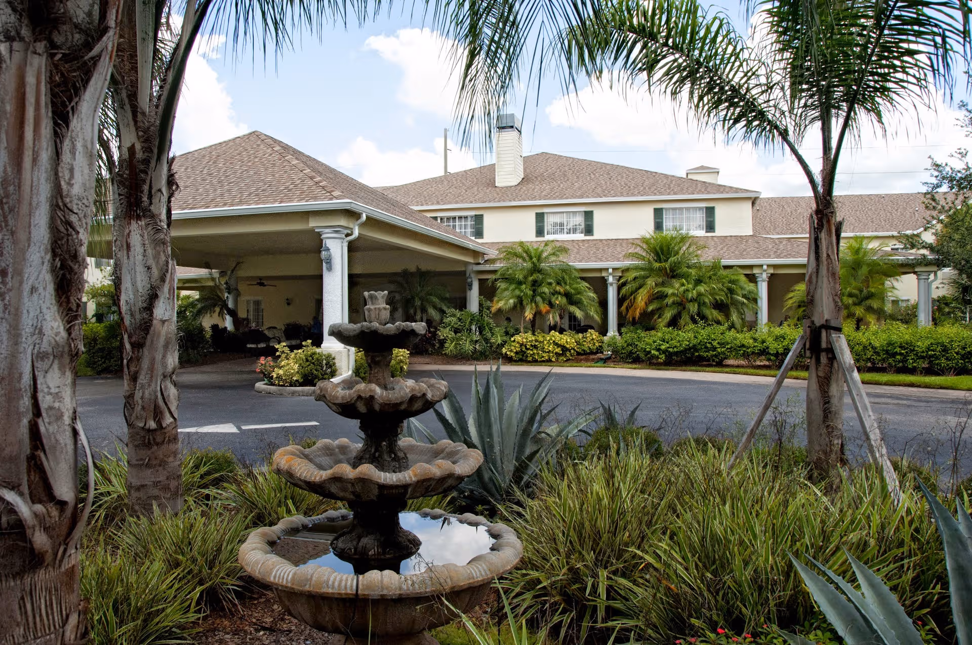 Exterior view of Lexington Manor with a tiered fountain and tropical landscaping.