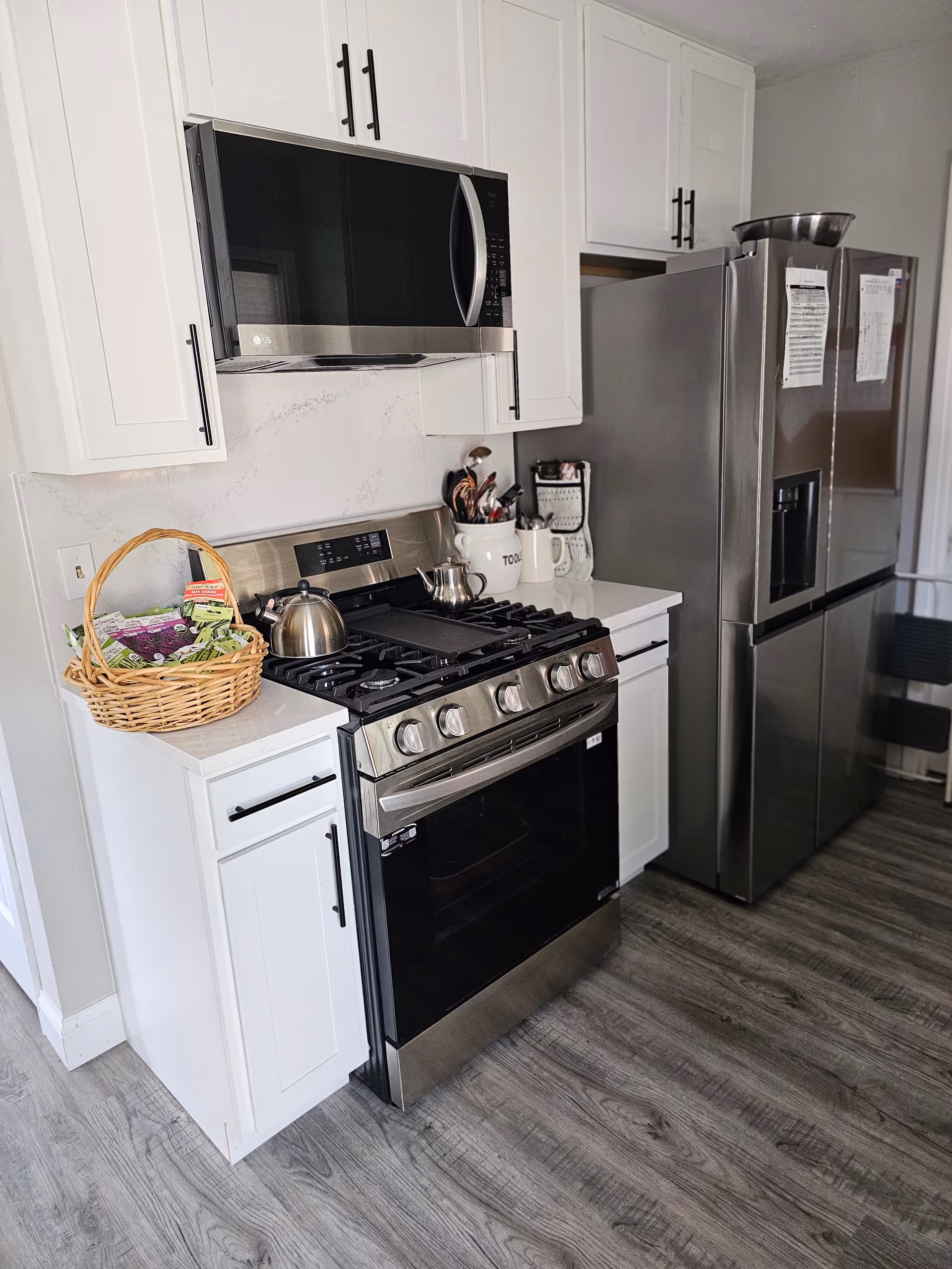 Bright kitchen with white cabinets, stainless appliances, and a basket on the counter.