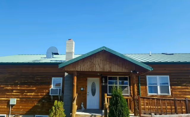 Log cabin-style senior living facility with a green metal roof and front porch.