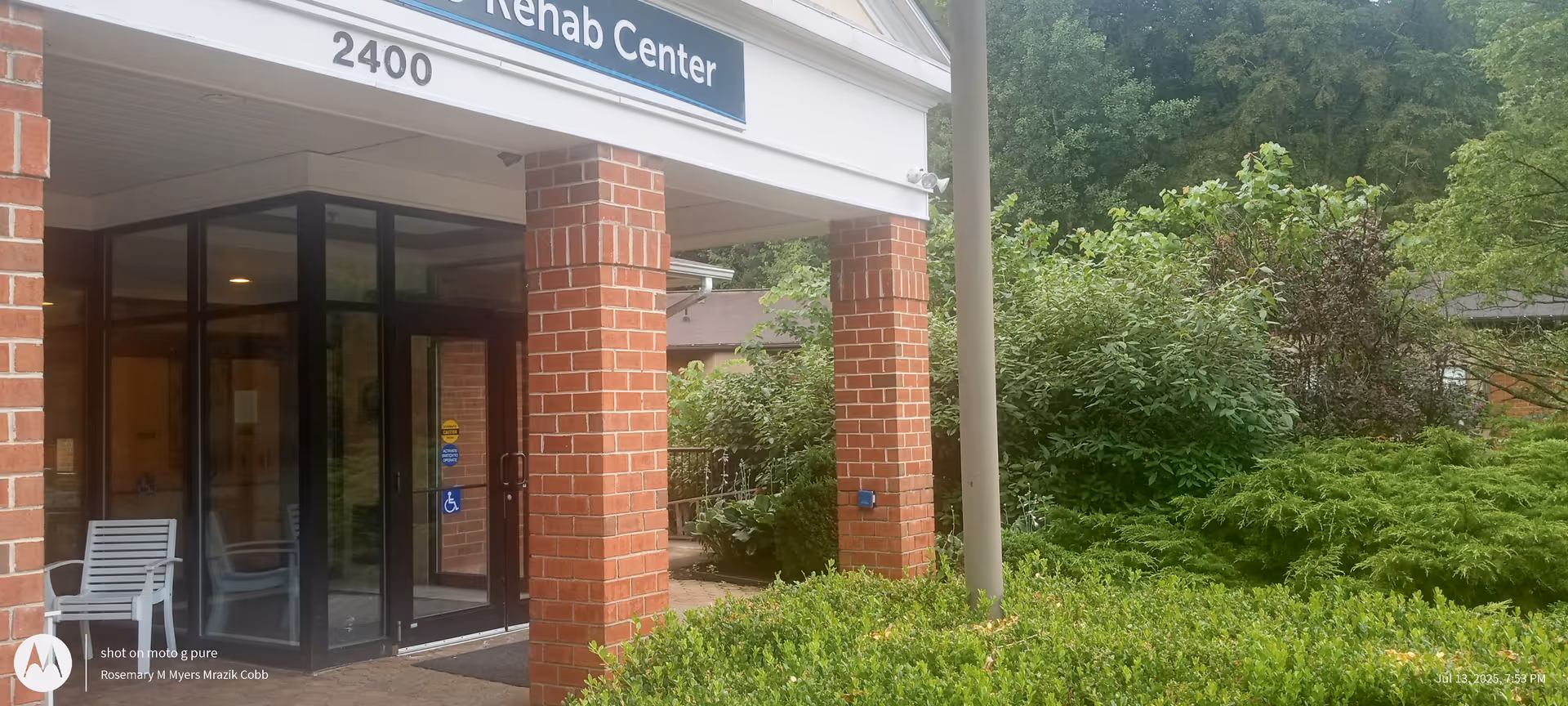 Exterior view of Woodhaven Care Center entrance with brick columns and glass doors.