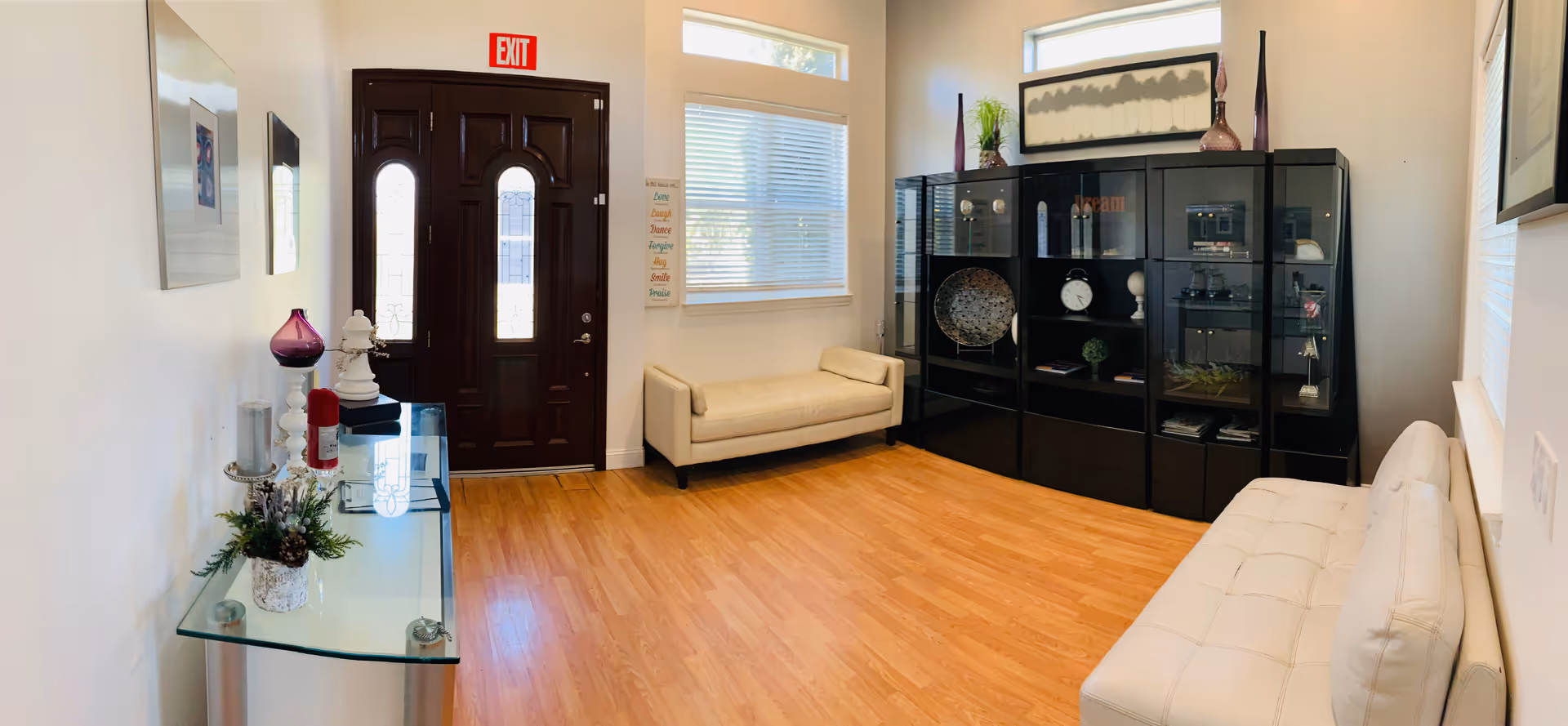 Bright interior lobby with white seating, glass console, and a large black display cabinet.