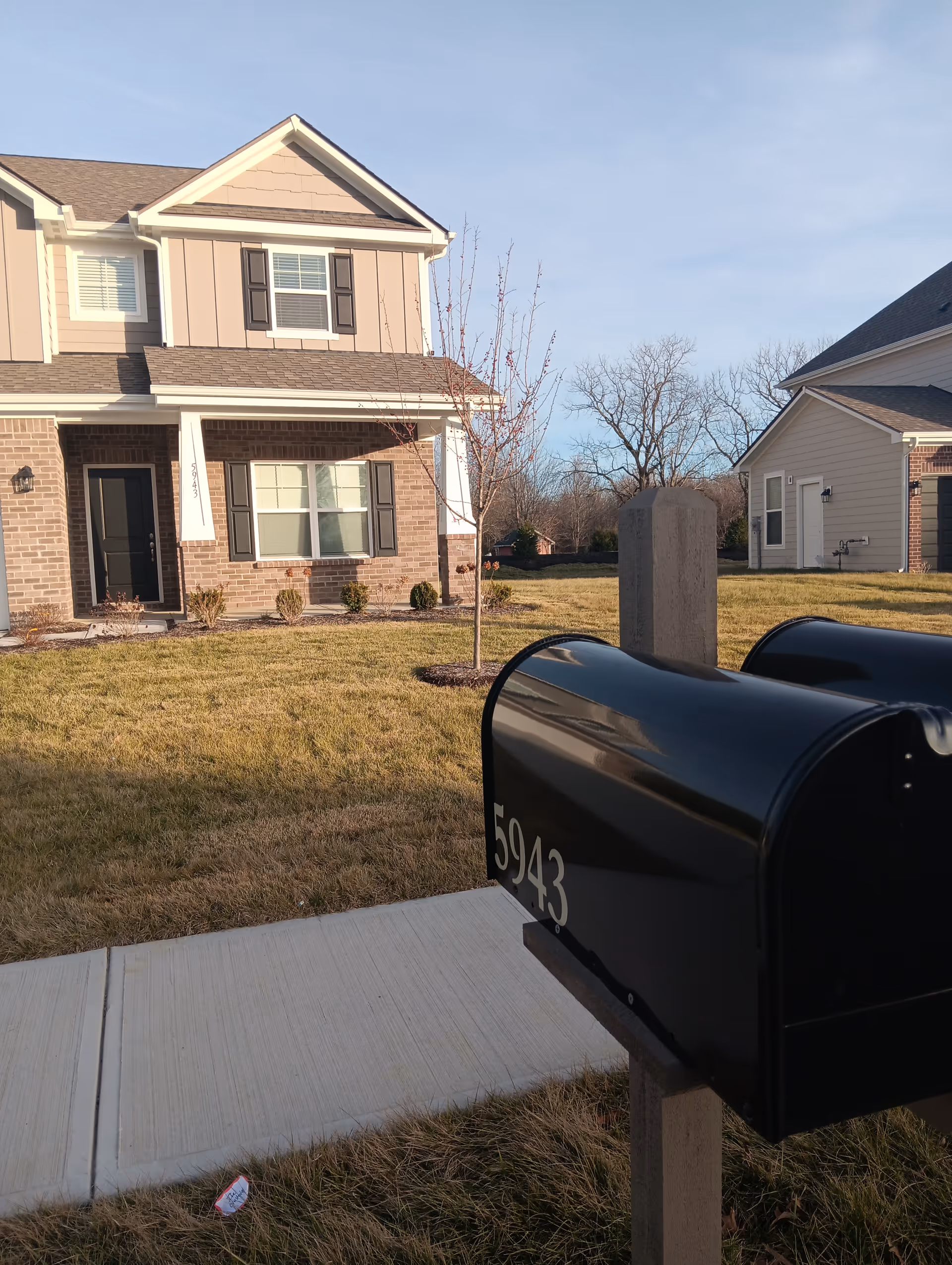Two-story brick house with a black mailbox in the front yard.