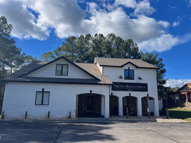 White two-story building with arched entrance and Virginia Realty Group sign.