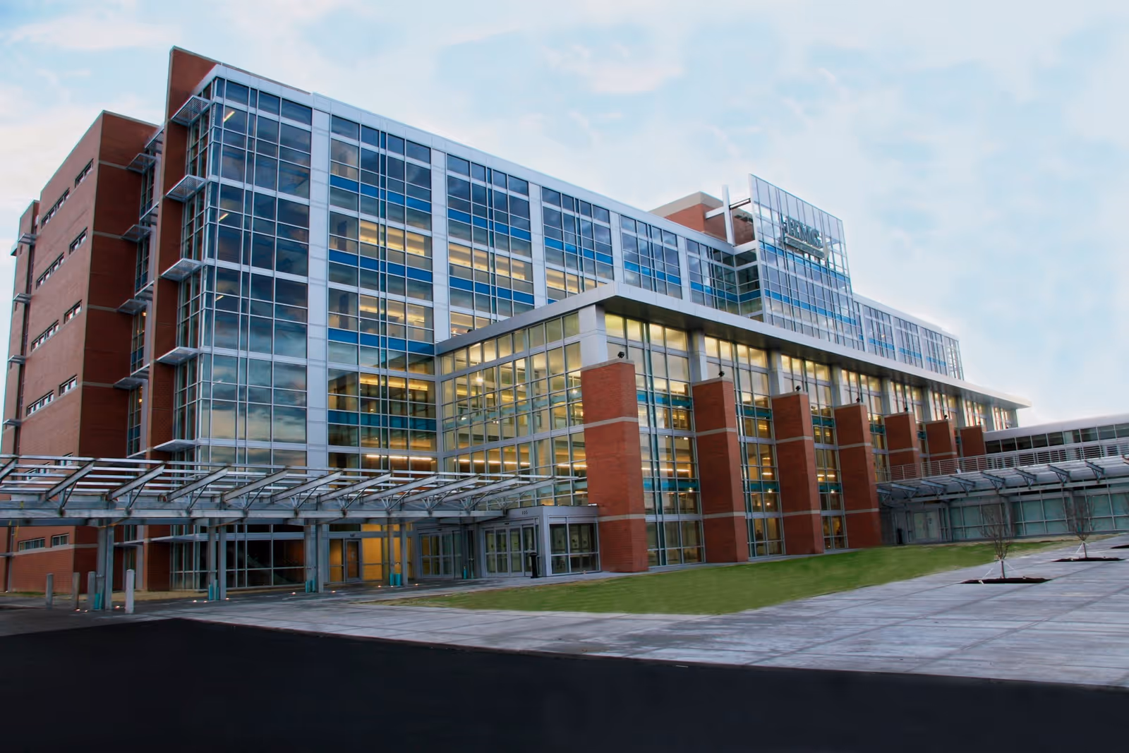 SunCrest Hospice exterior with a modern glass facade, brick columns, and an entry canopy.