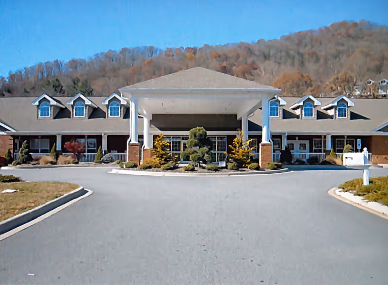 Exterior view of a senior living center with a covered entrance and landscaped circle.