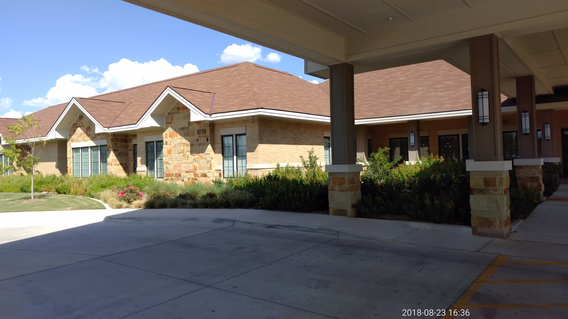 Brick-and-stone hospice building with a covered entrance and landscaped shrubs.